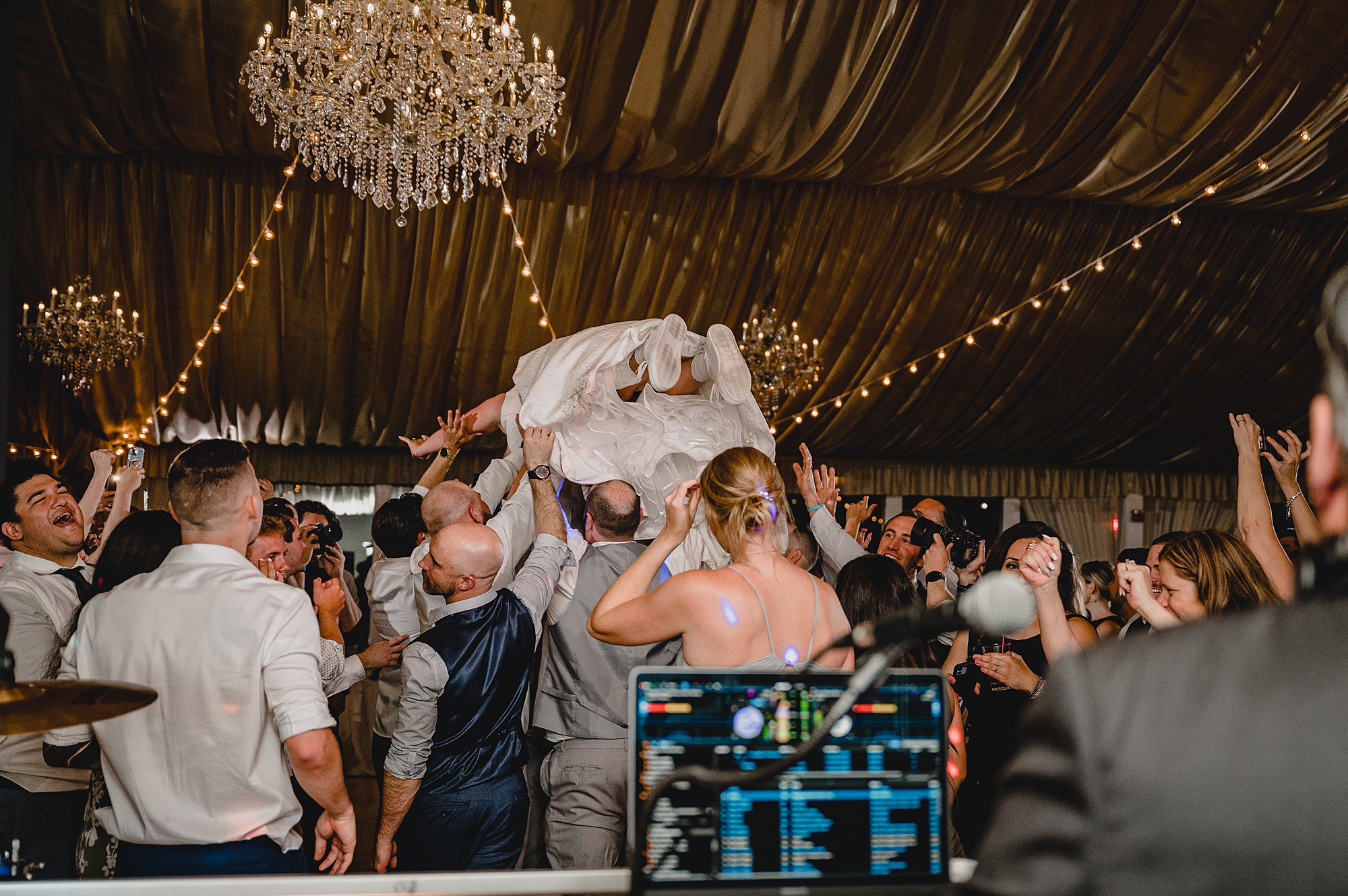 bride jumps on wedding guests holding her in the air