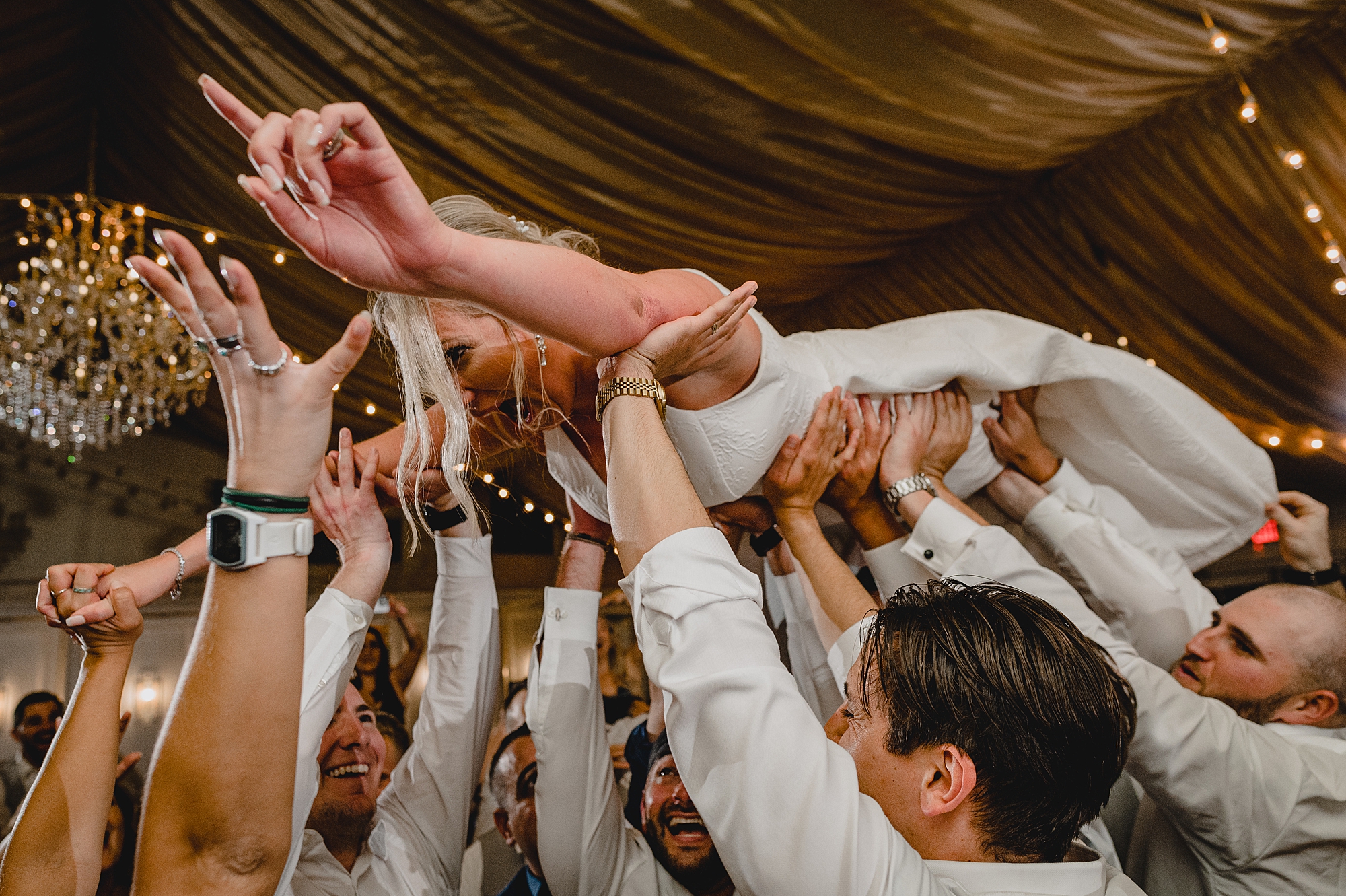 bride jumps on wedding guests holding her in the air