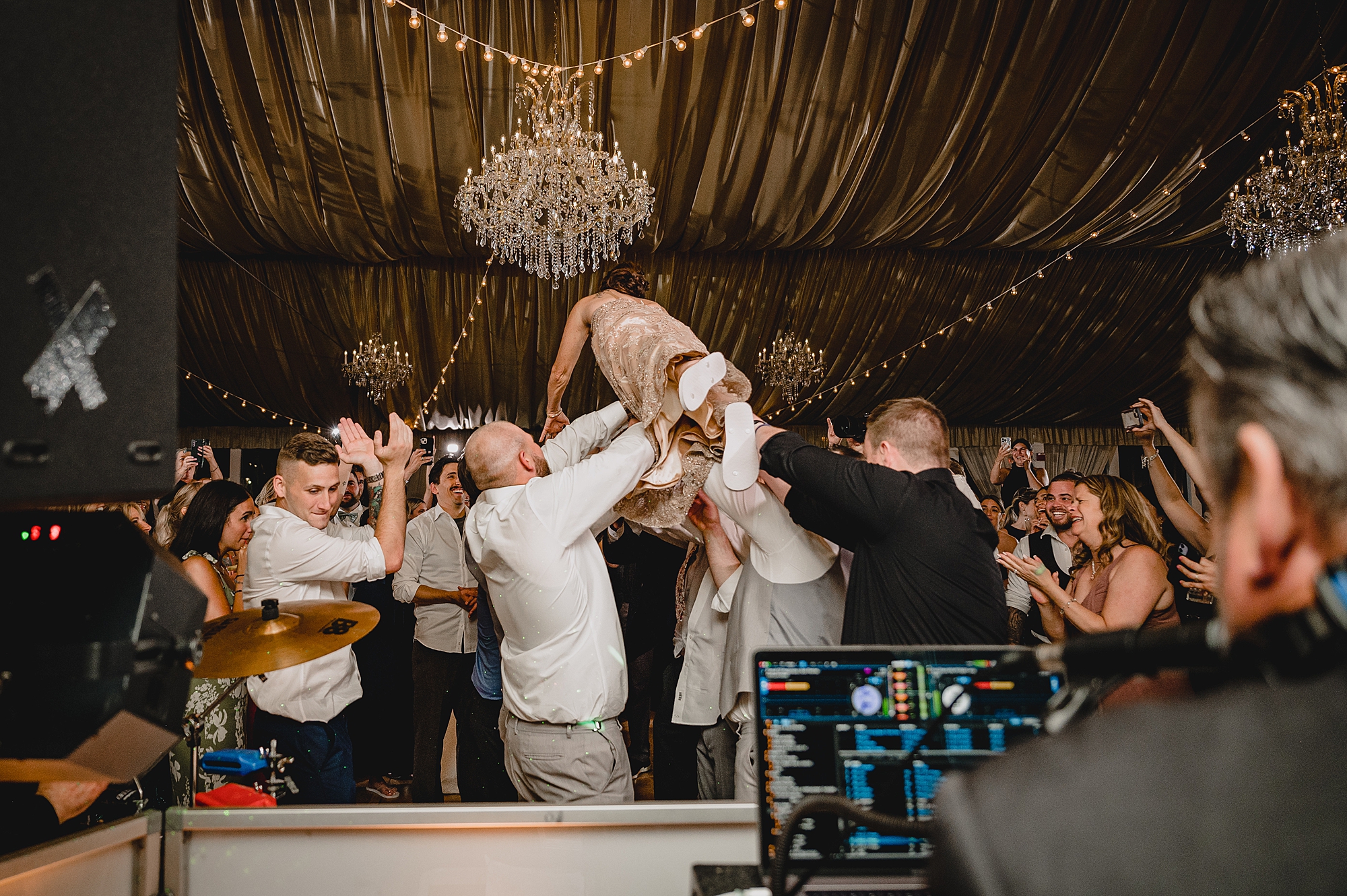 bride jumps on wedding guests holding her in the air