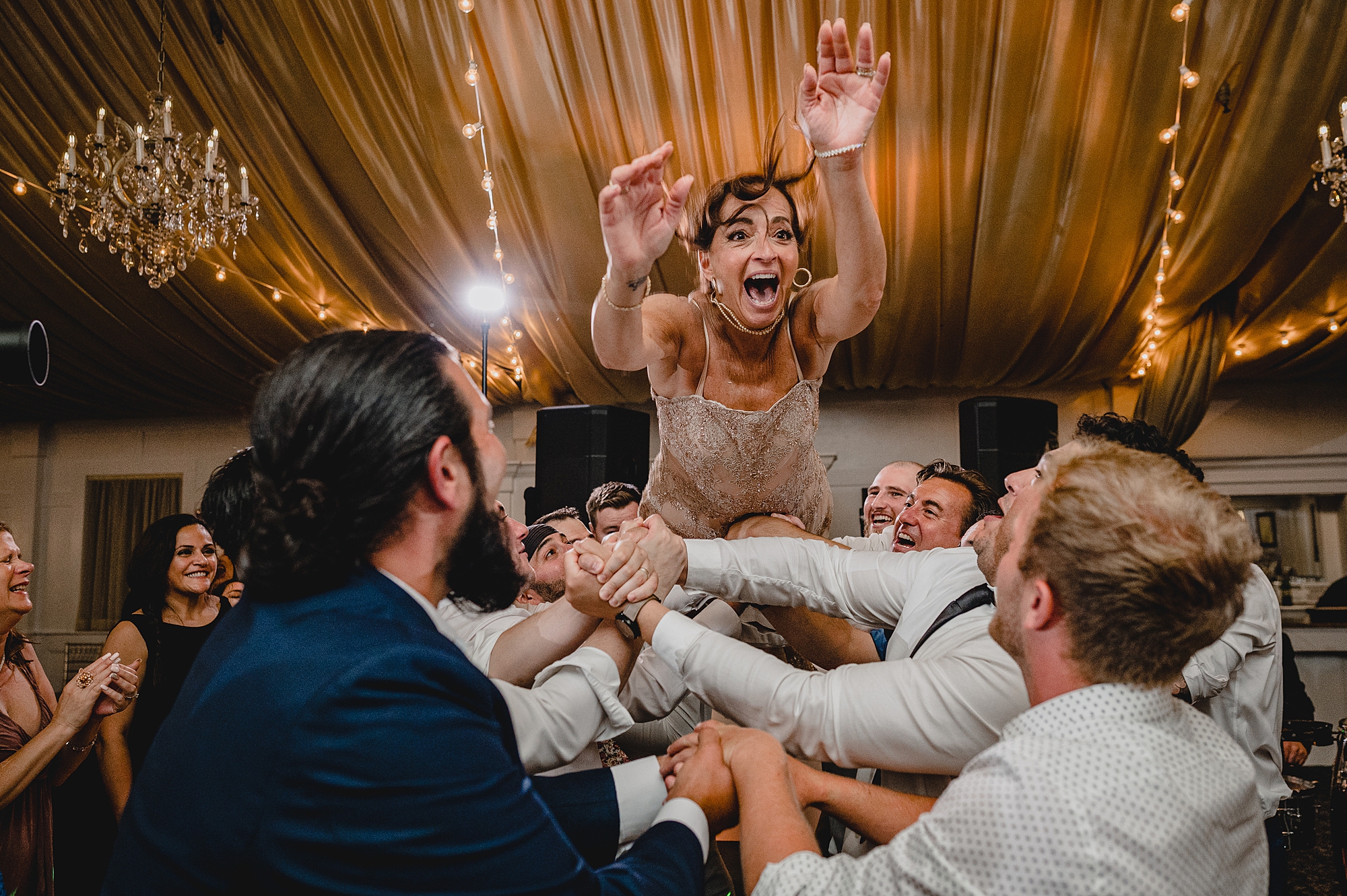 bridesmaid jumps on wedding guests holding her in the air