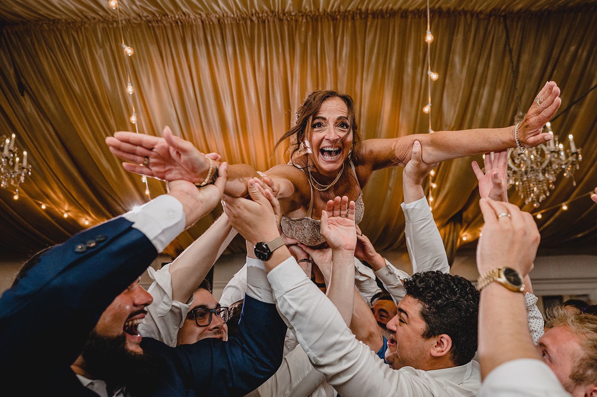 bridesmaid jumps on wedding guests holding her in the air