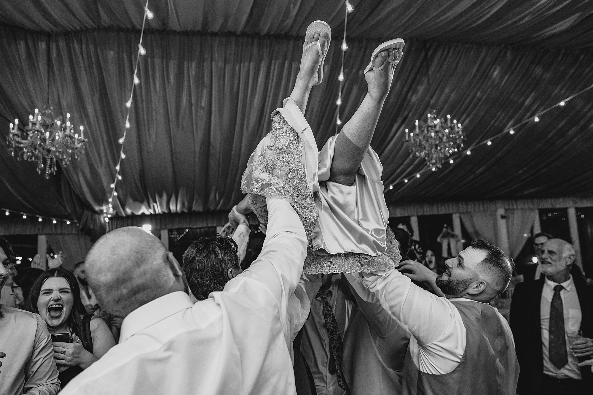 bridesmaid jumps on wedding guests holding her in the air