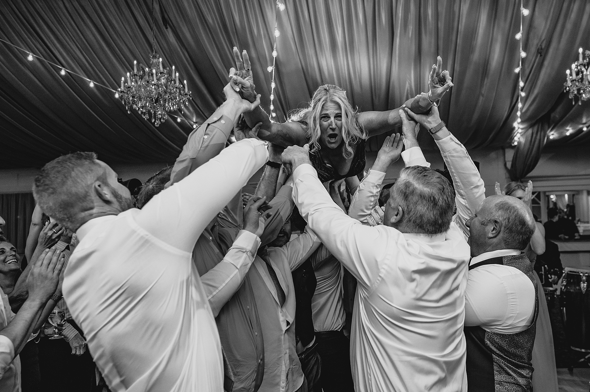 bride jumps on wedding guests holding her in the air
