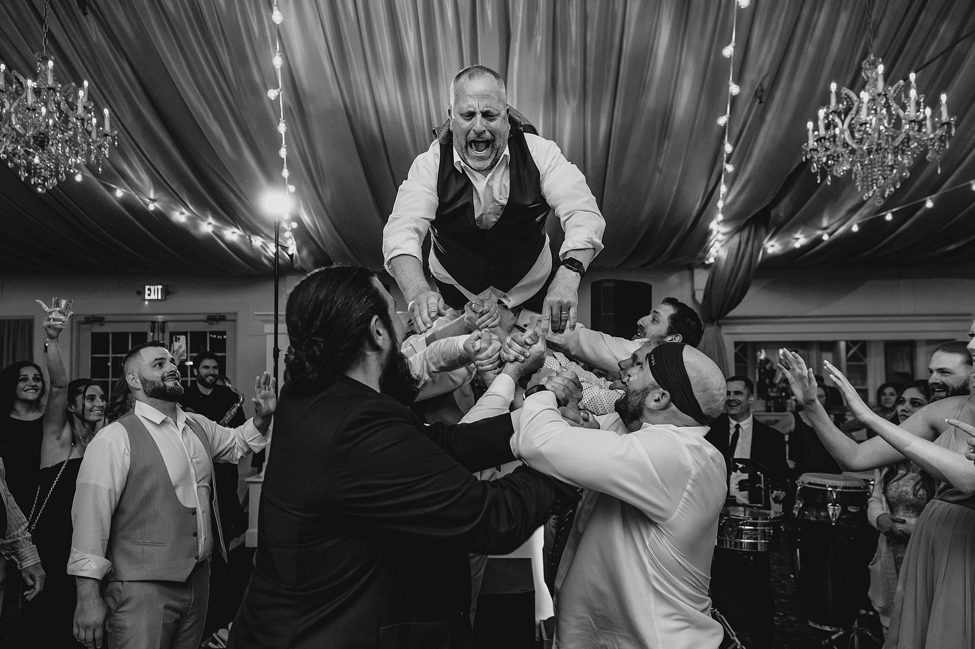 dad of bride jumps on wedding guests holding him in the air