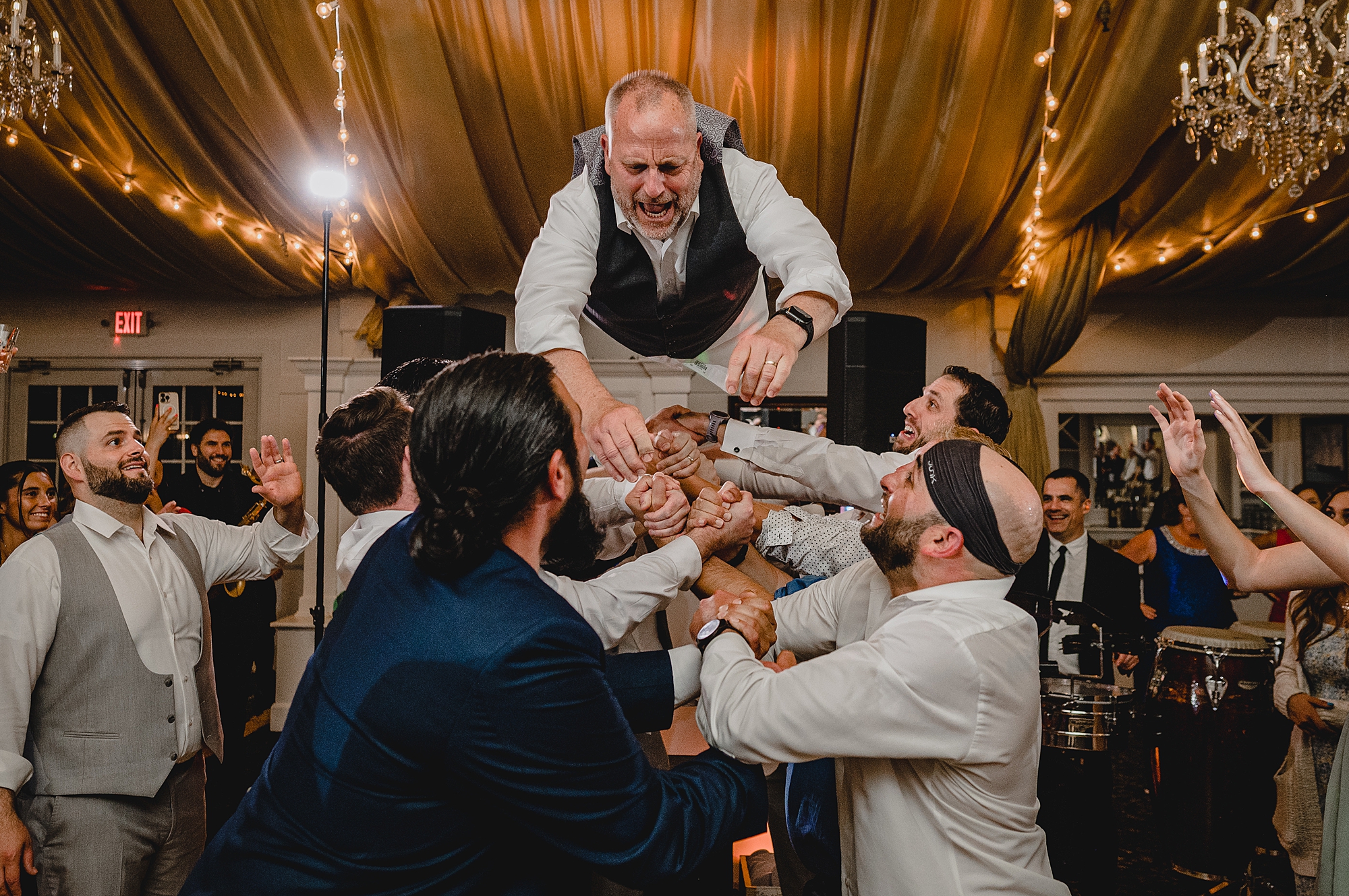 dad of bride jumps on wedding guests holding him in the air