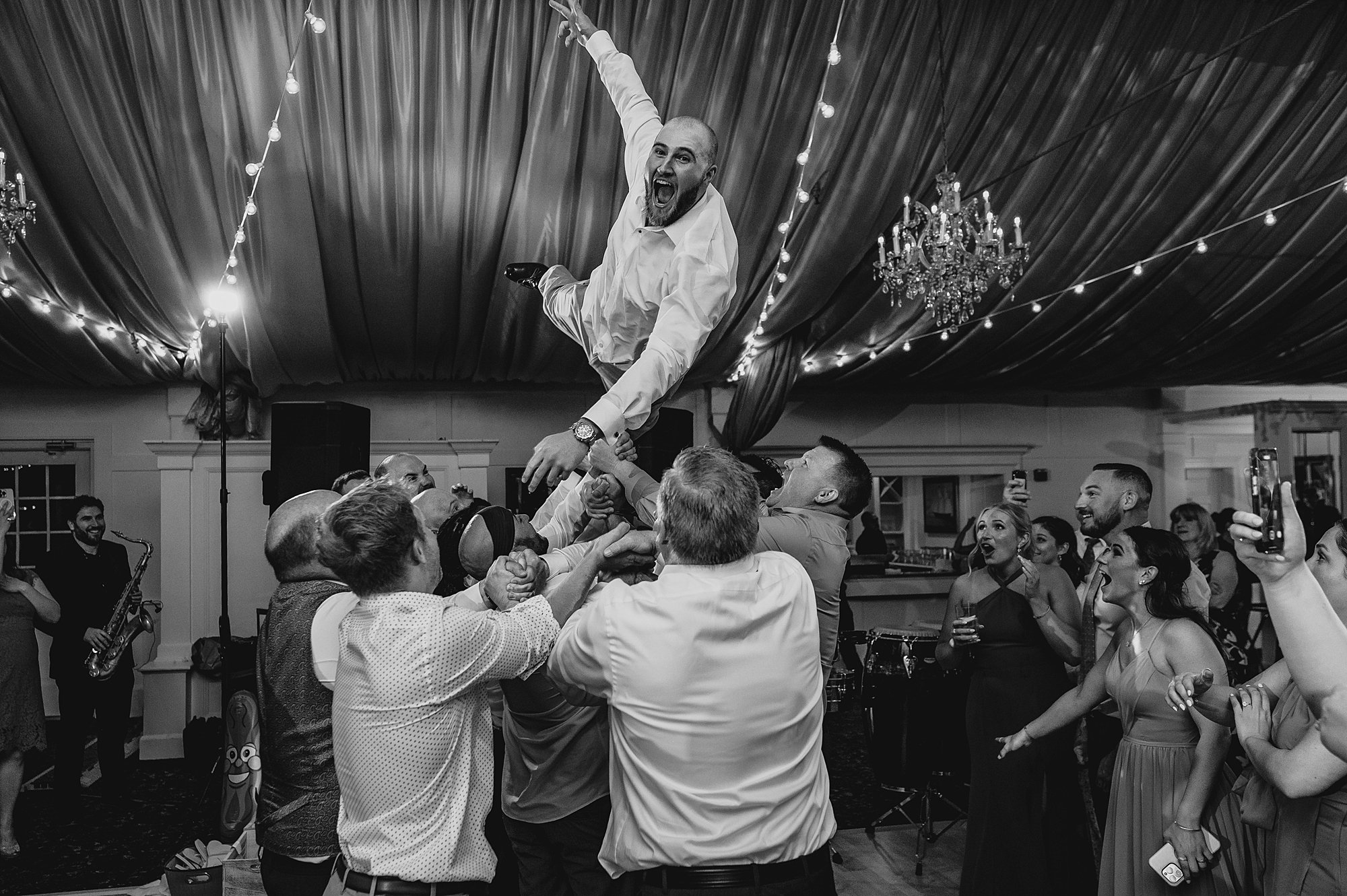 dad of bride jumps on wedding guests holding him in the air