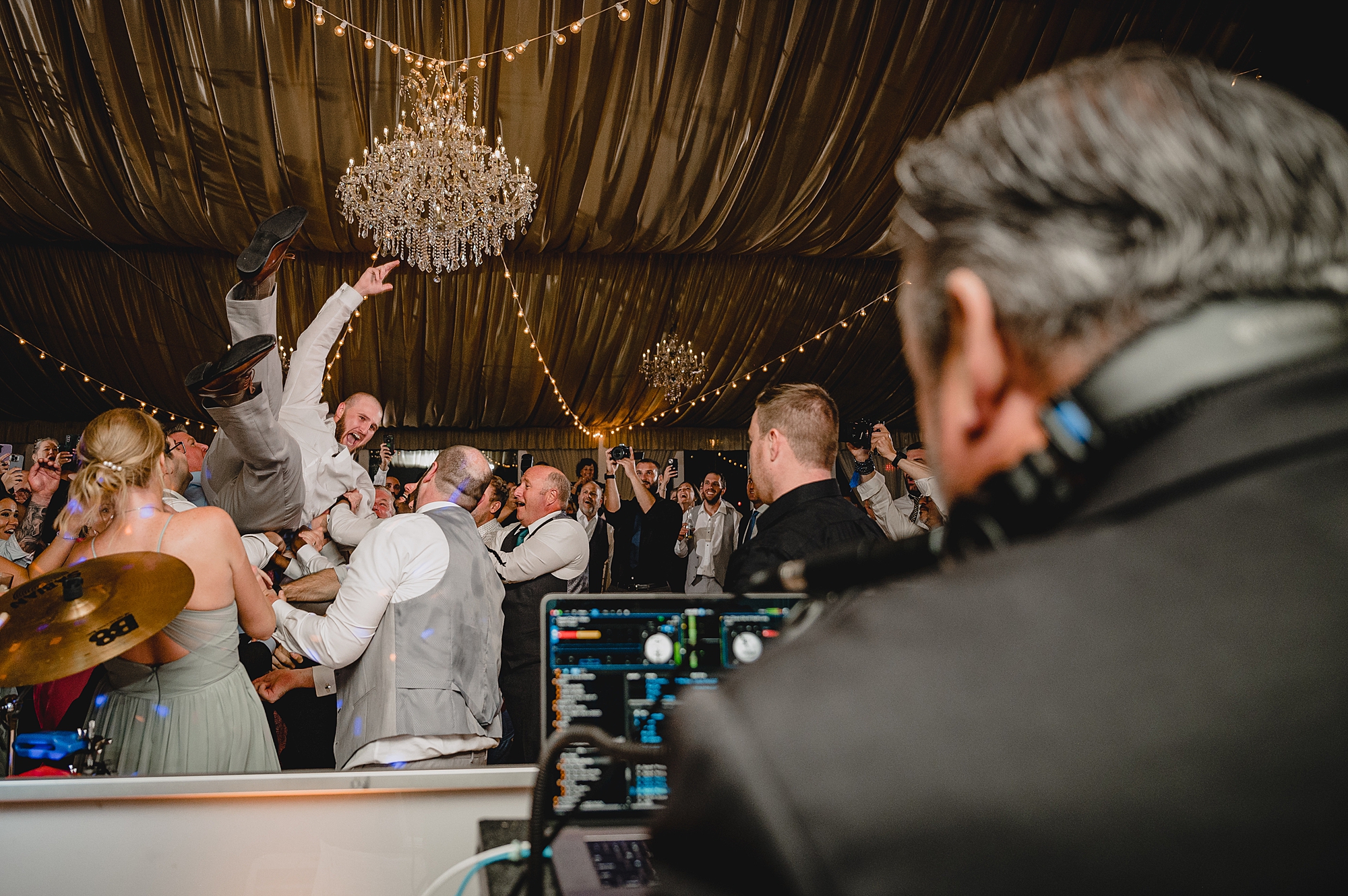 dad of bride jumps on wedding guests holding him in the air