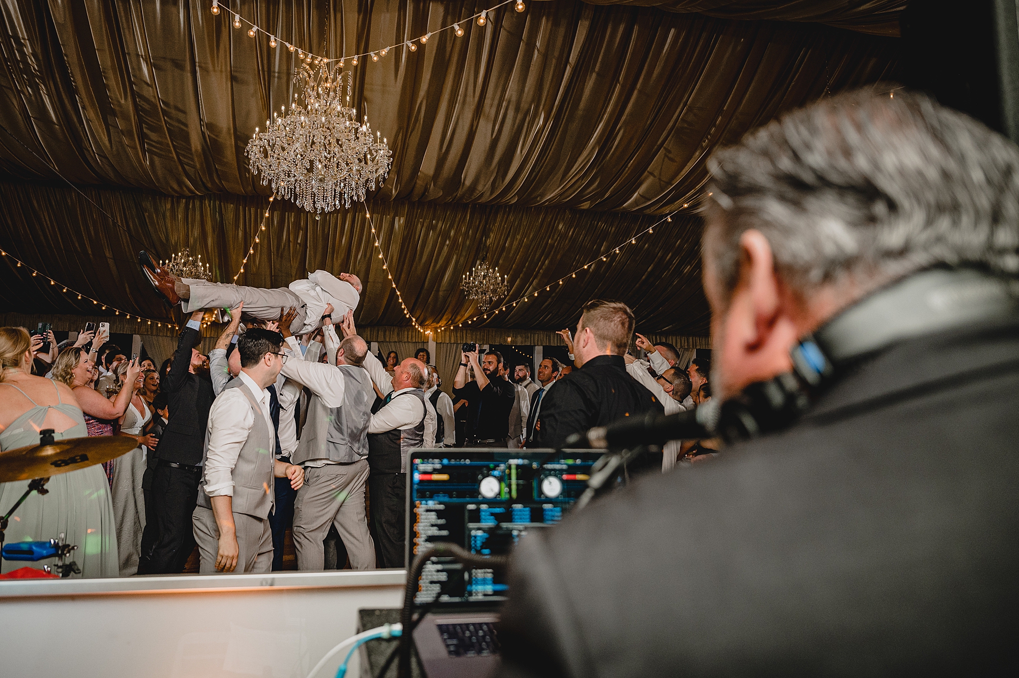 dad of bride jumps on wedding guests holding him in the air