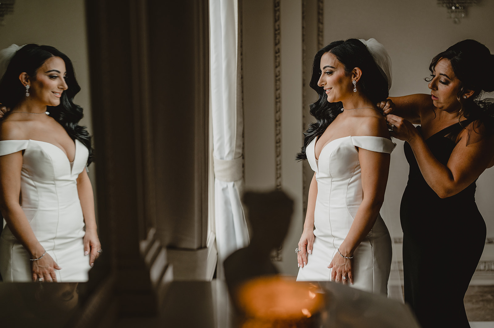 mother helps bride with the back of her wedding gown
