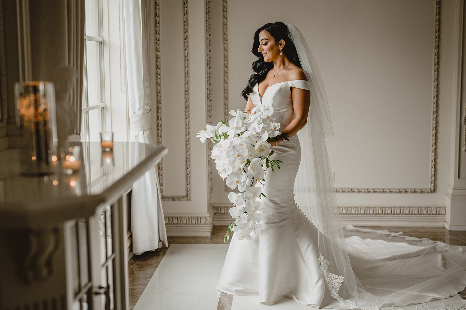 bride holds cascading bouquet of white orchids in suite at the Venetian