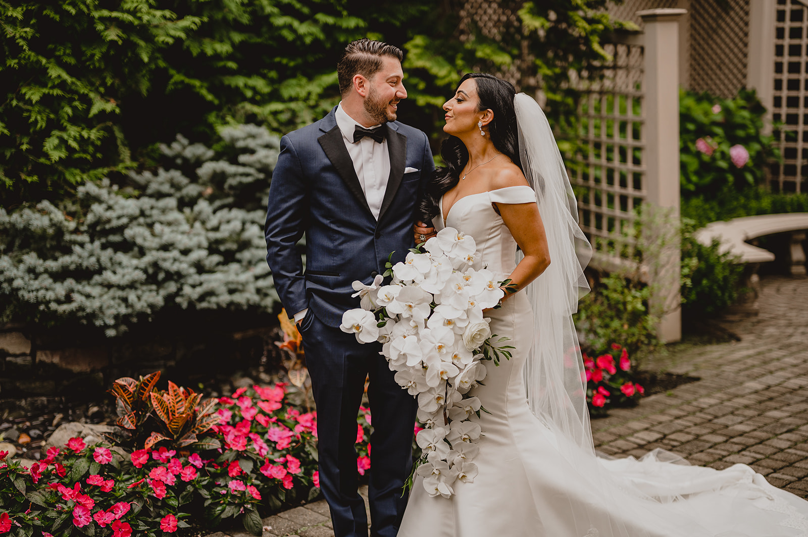 bride and groom smile together in front of trellis in gardens of the Venetian