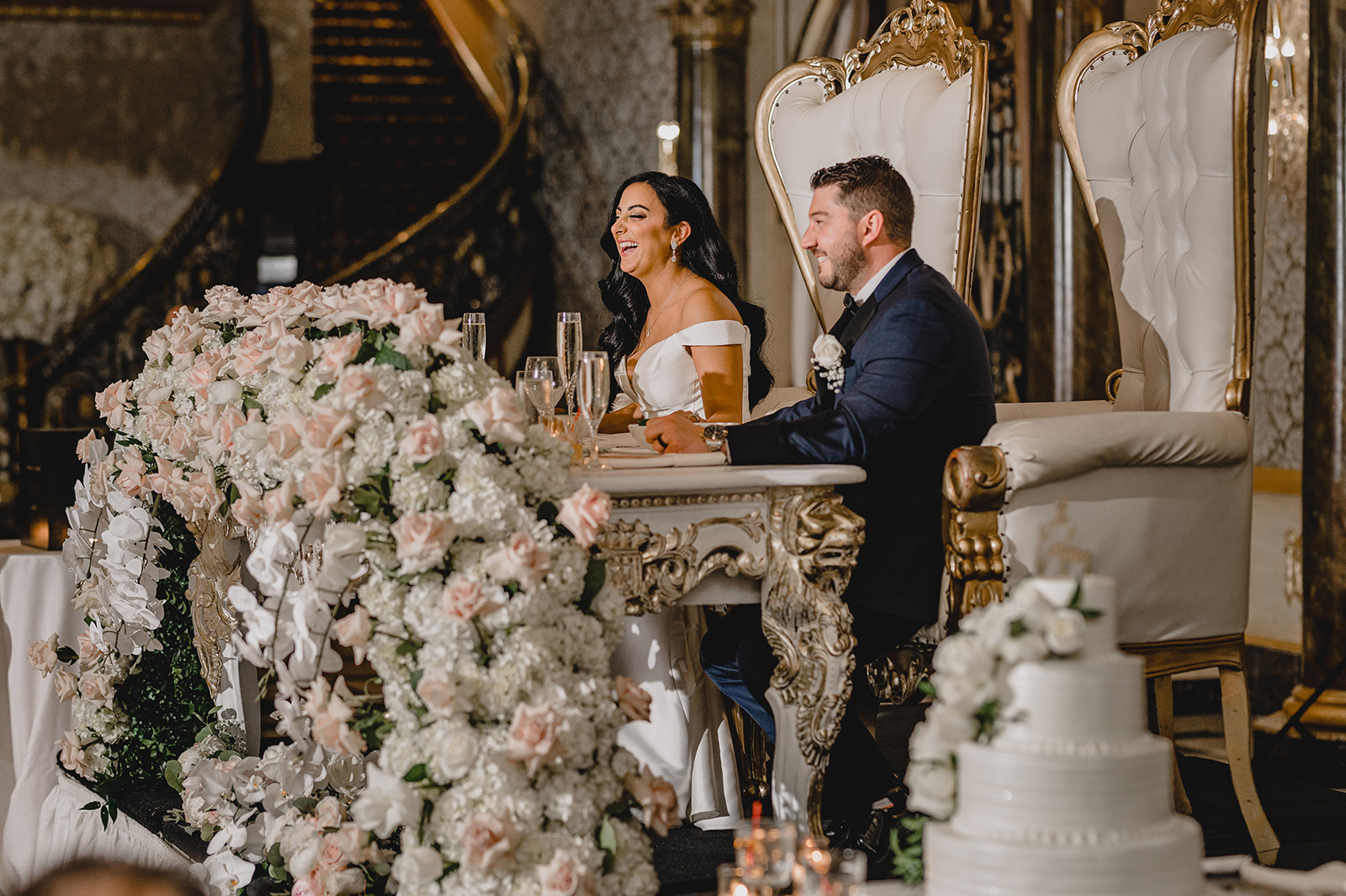 bride and groom sit at sweetheart table listening to speeches