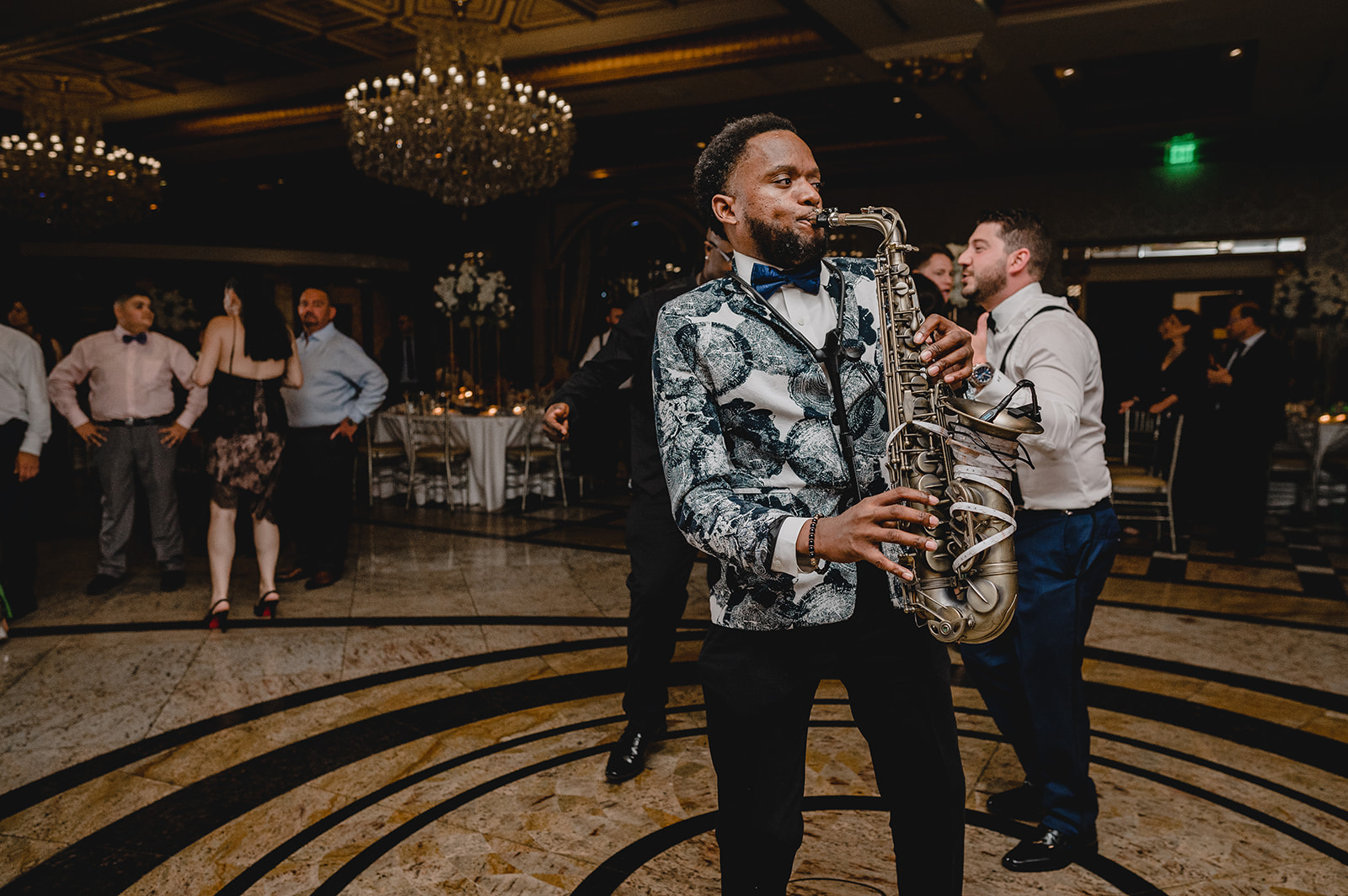 black man plays saxophone in black and white blazer