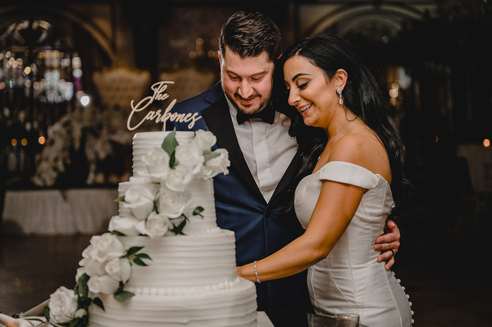 bride and groom hug cutting wedding cake