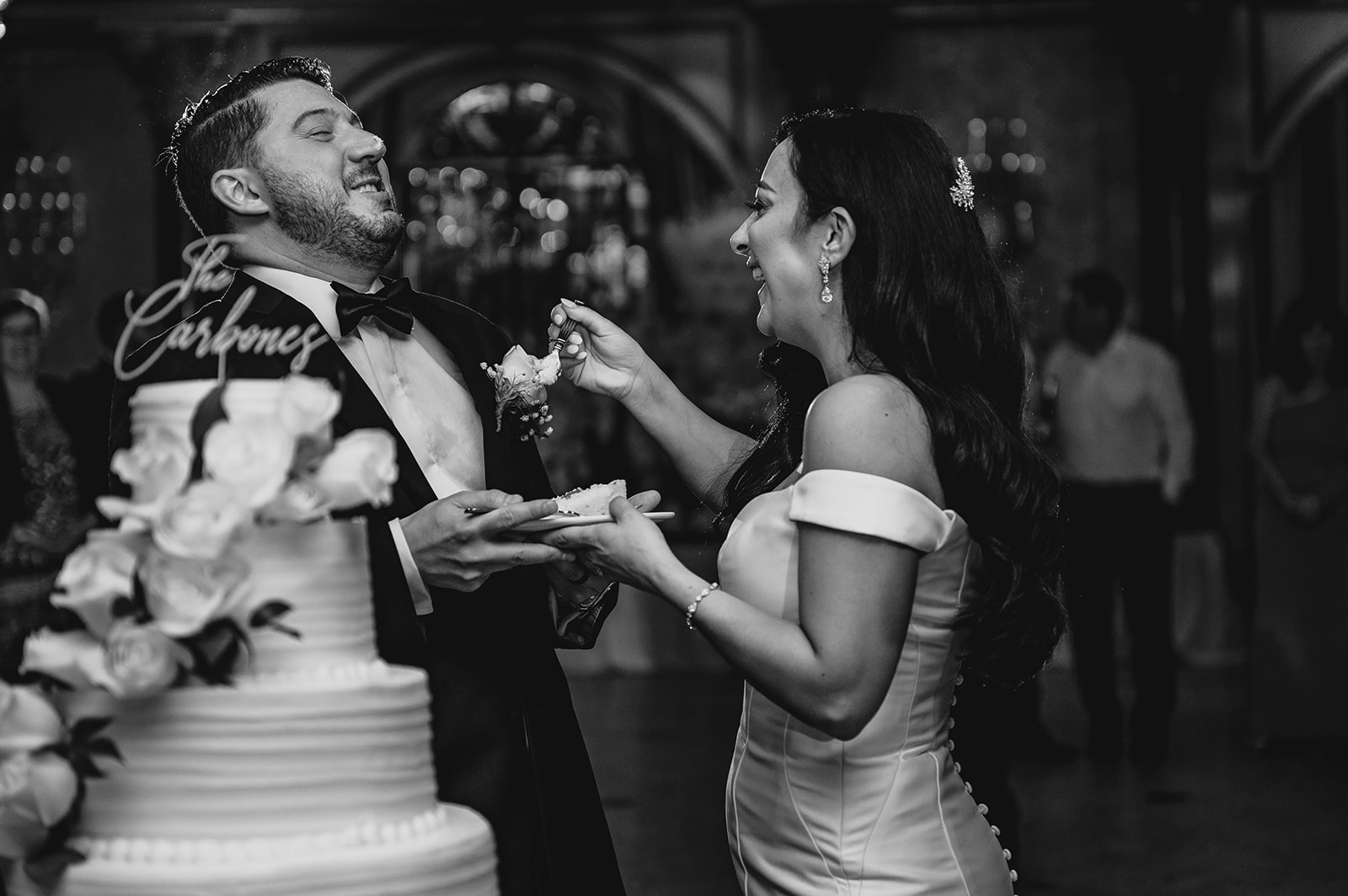 newlyweds laugh feeding each other cake at reception 