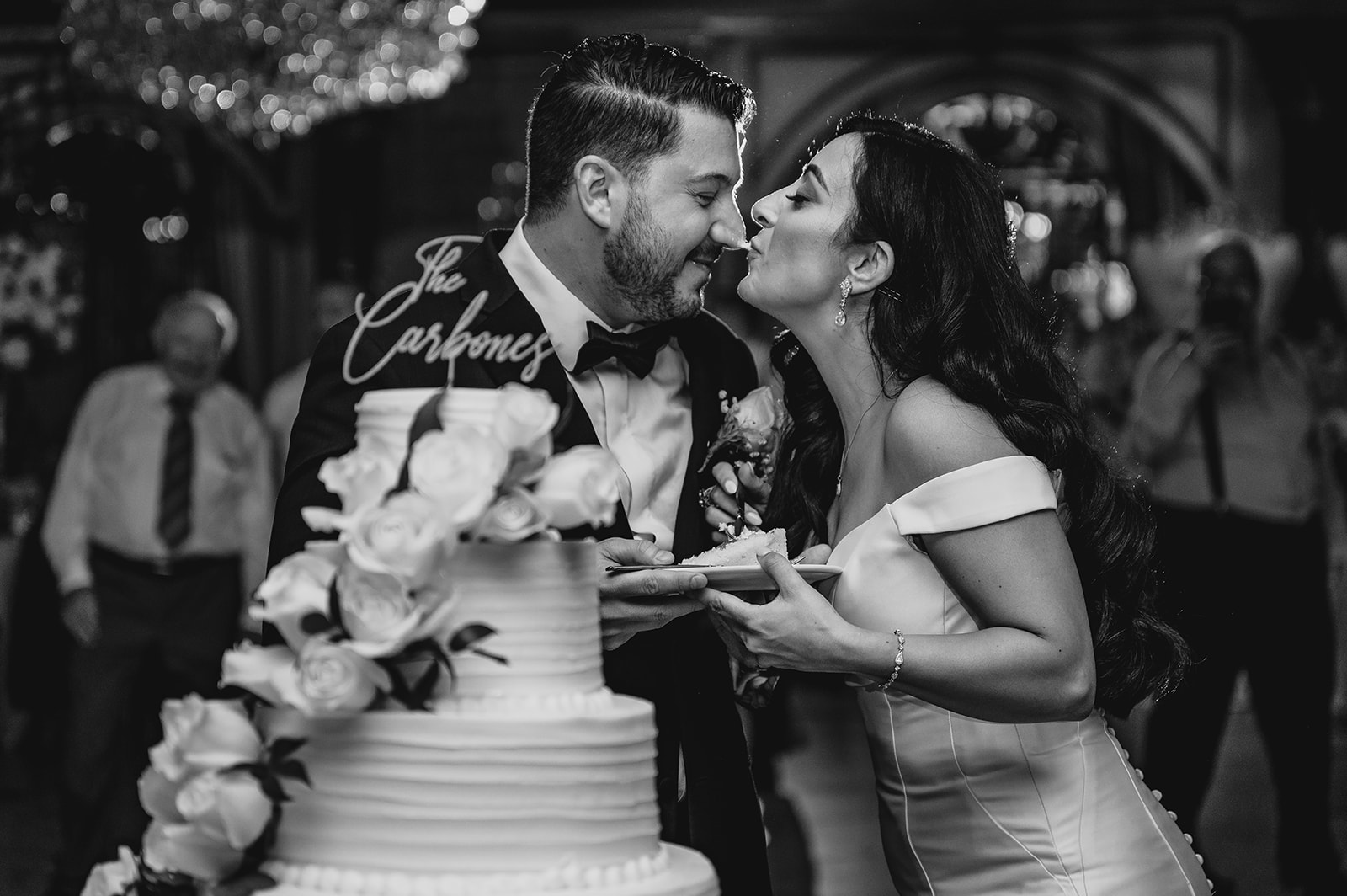 bride and groom kiss after sharing cake at wedding reception