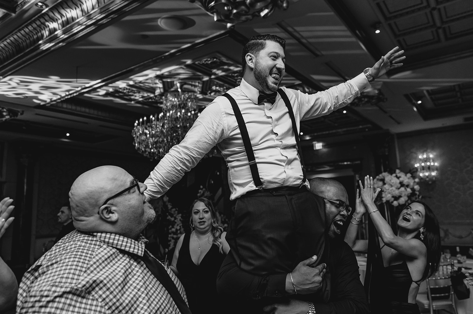 guests lift up groom on their shoulders during wedding reception