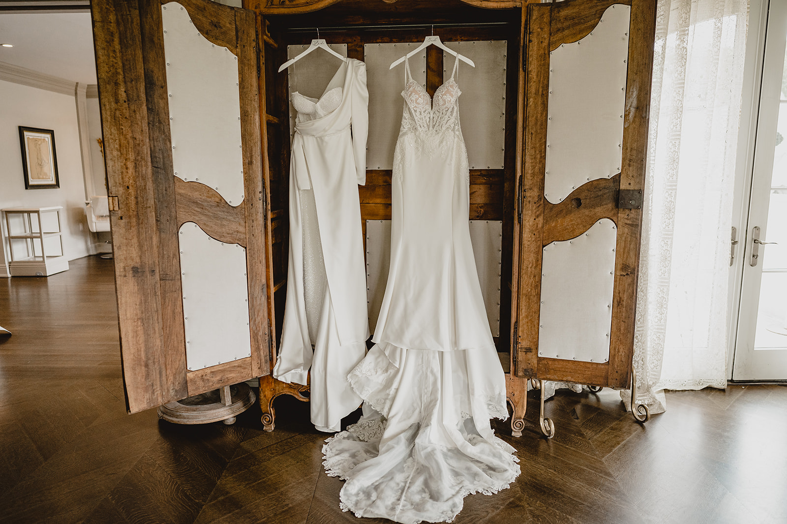 two wedding gowns hang in armoire at Park Chateau Estate bridal suite