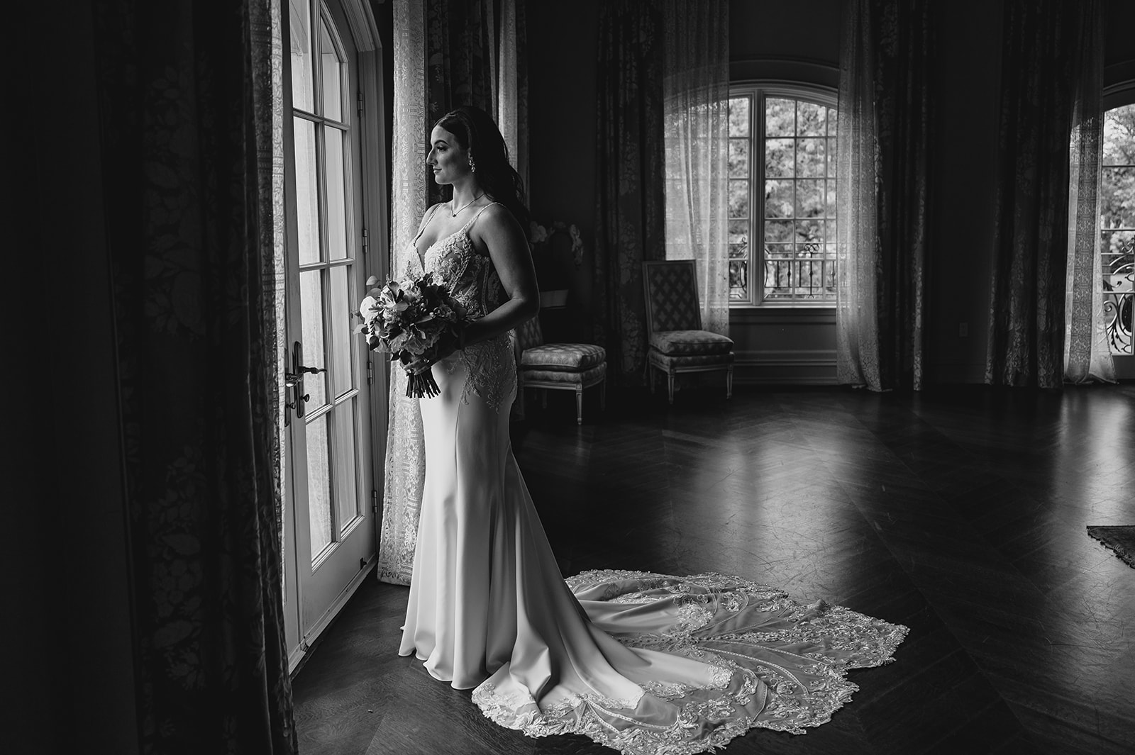 bride holds bouquet in front of window of bridal suite at Park Chateau Estate