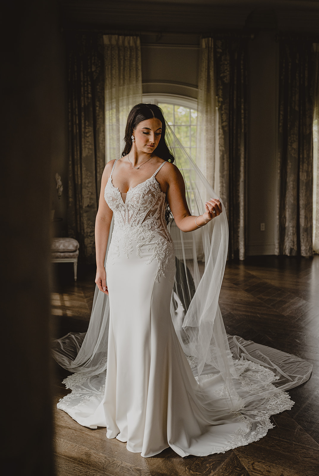 bride pulls veil around her shoulders standing inside the bridal suite at Park Chateau Estate