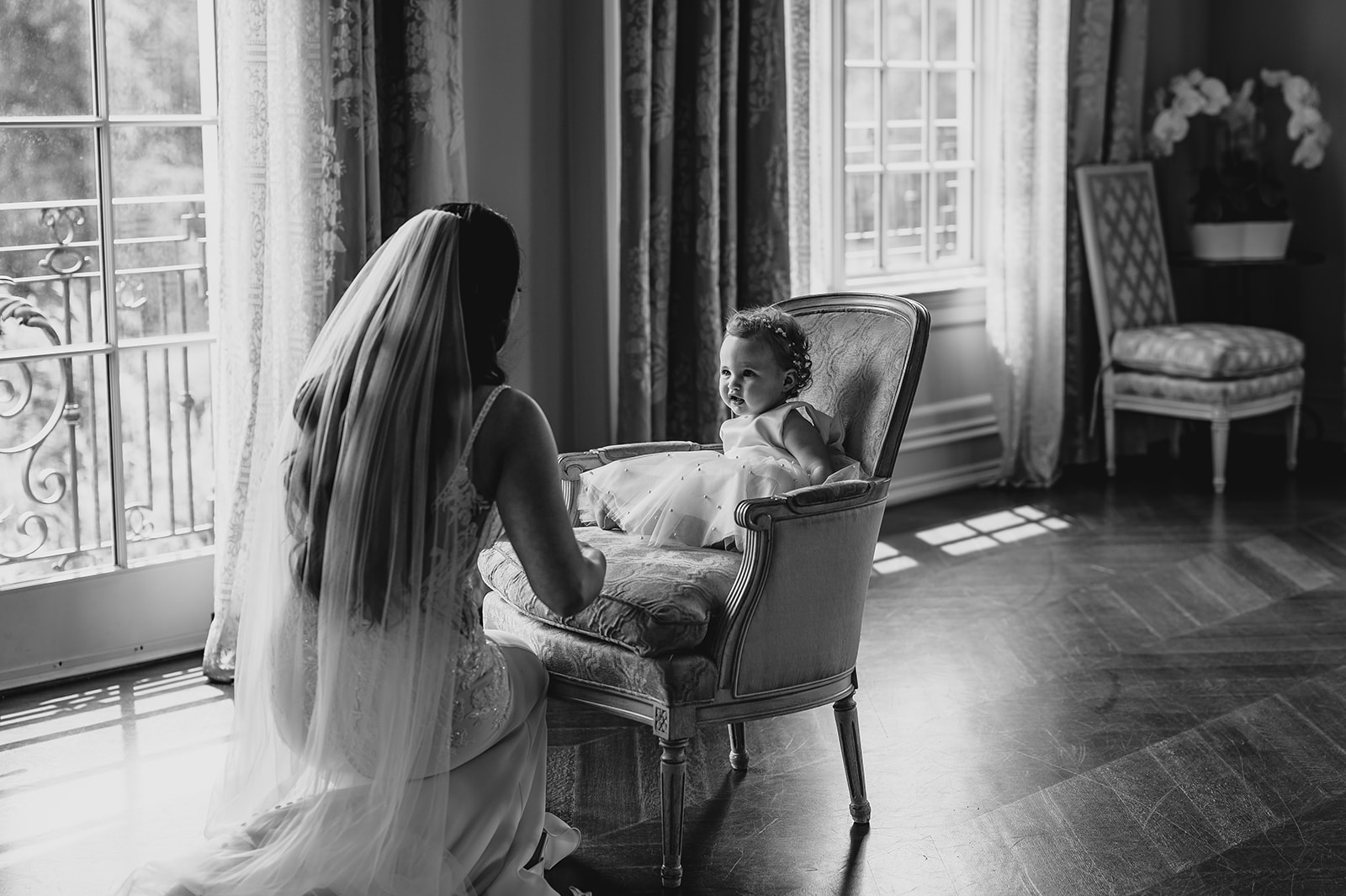 bride kneels down to talk with flower girl