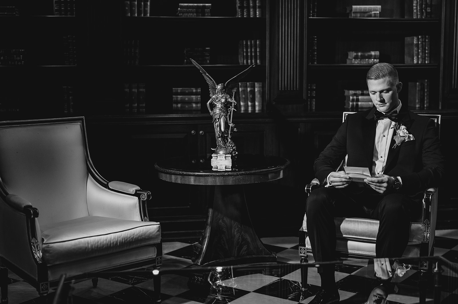 groom sits in the library at Park Chateau Estate reading letter