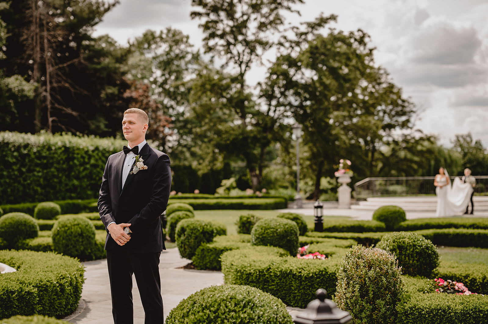 bride approaches groom walking through garden at Park Chateau Estate