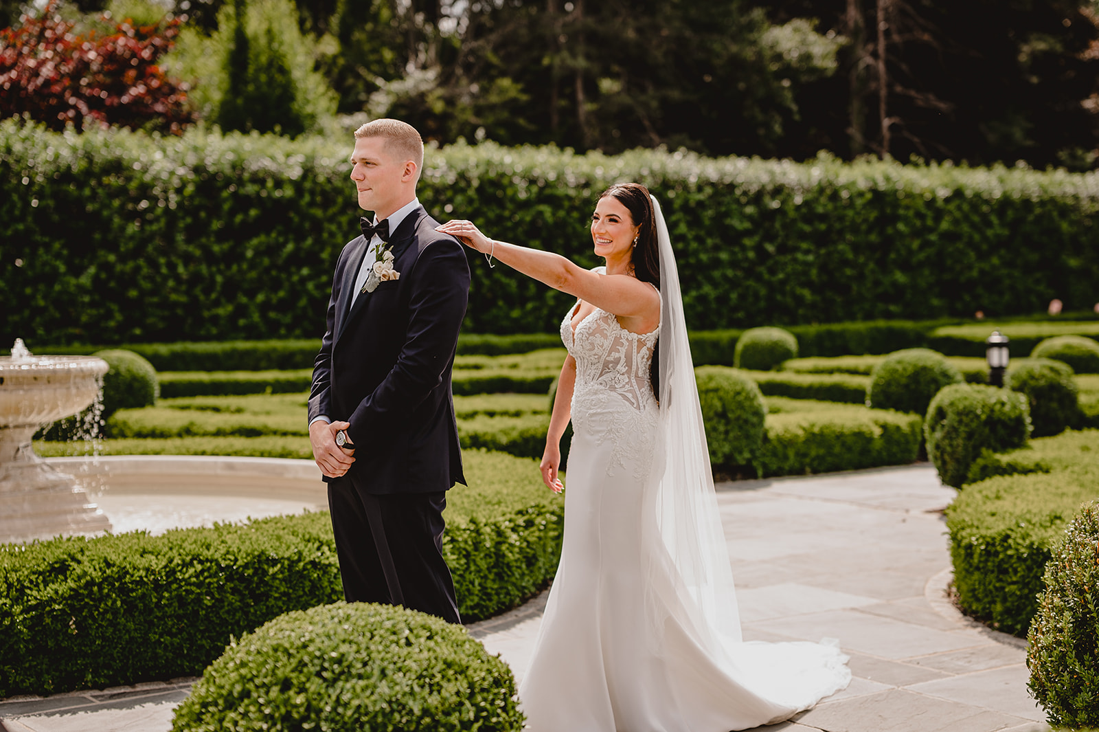 bride reaches for groom in gardens of Park Chateau Estate