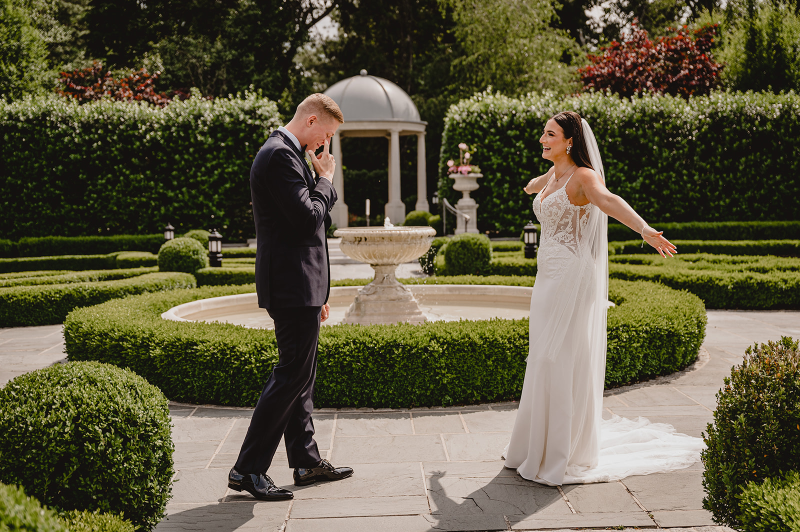 groom cries looking at bride holding her arms out