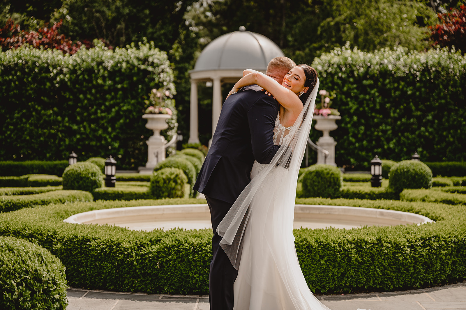 newlyweds hug in gardens of Park Chateau Estate