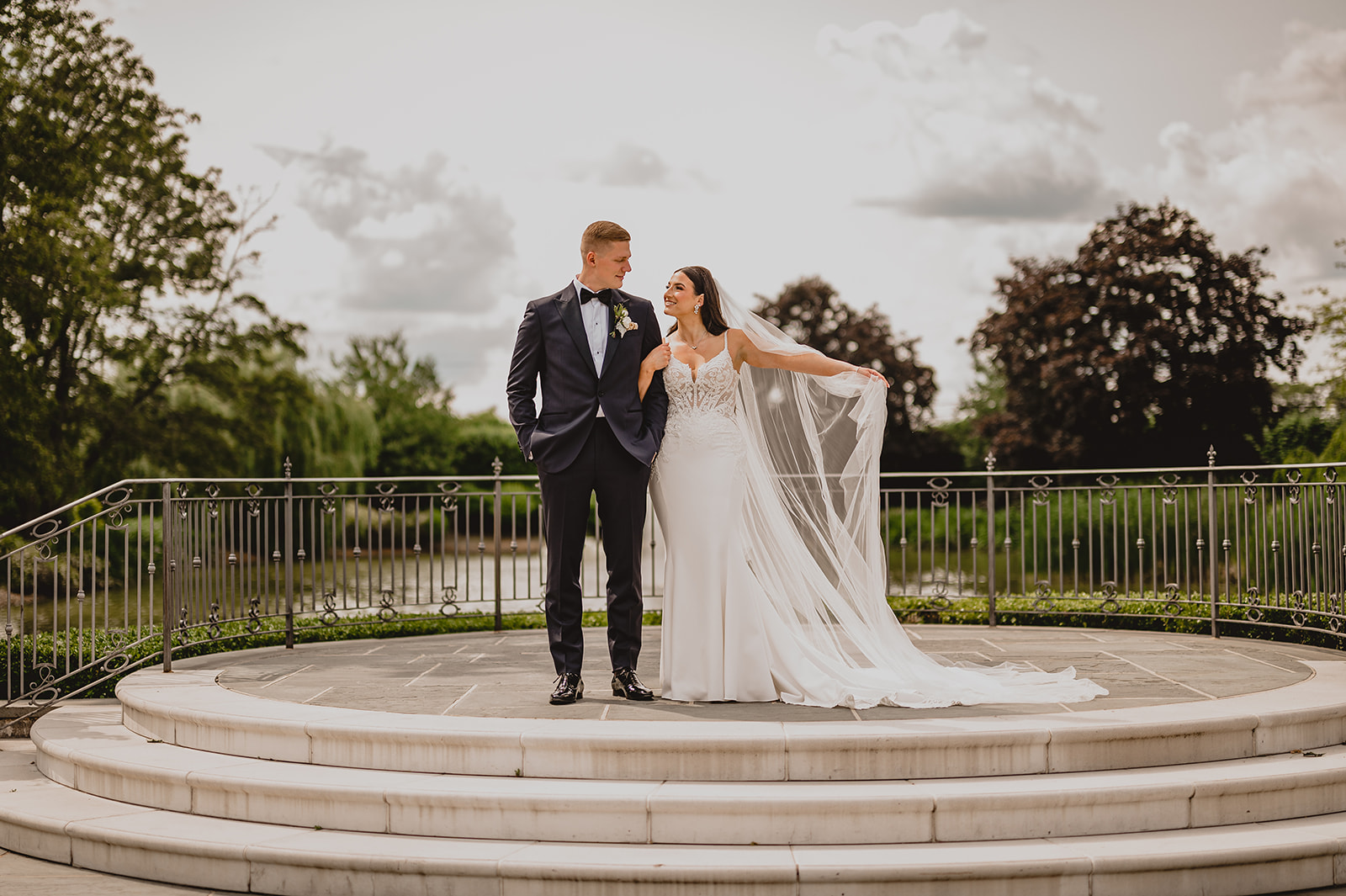 bride and groom stand on stone patio in gardens of Park Chateau Estate