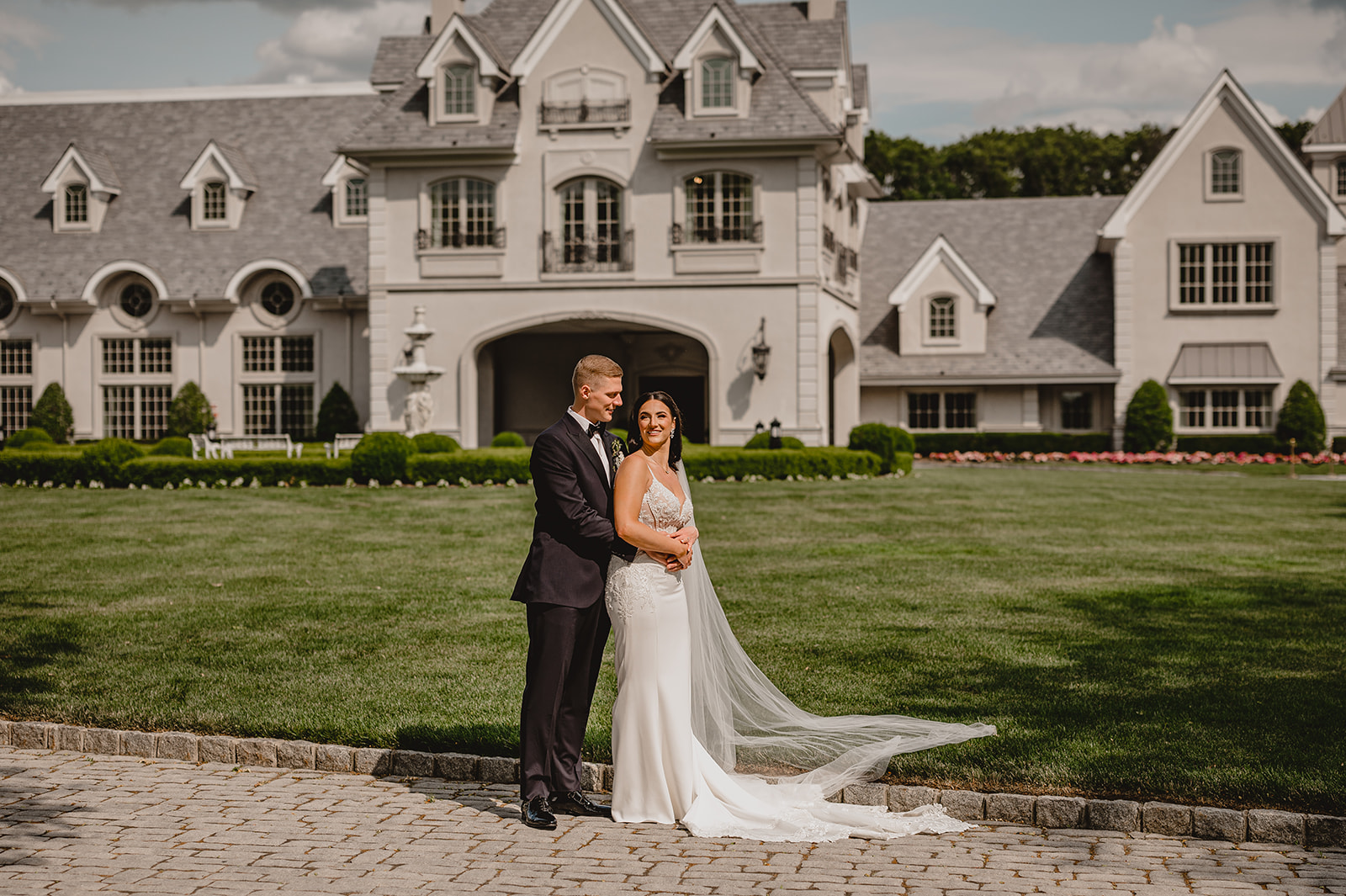 groom hugs bride from behind in front of Park Chateau Estate