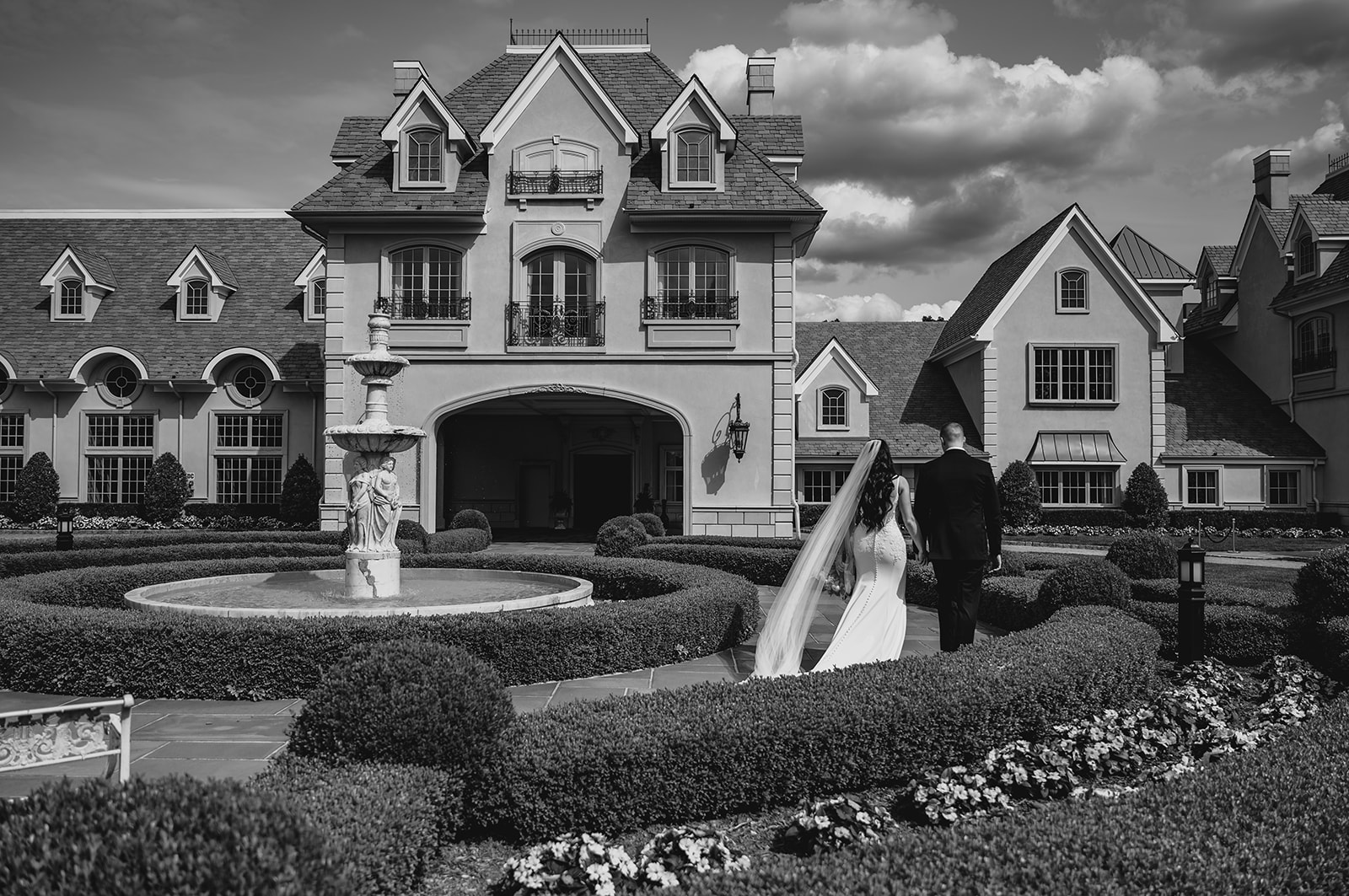 newlyweds walk by fountain in front of Park Chateau Estate
