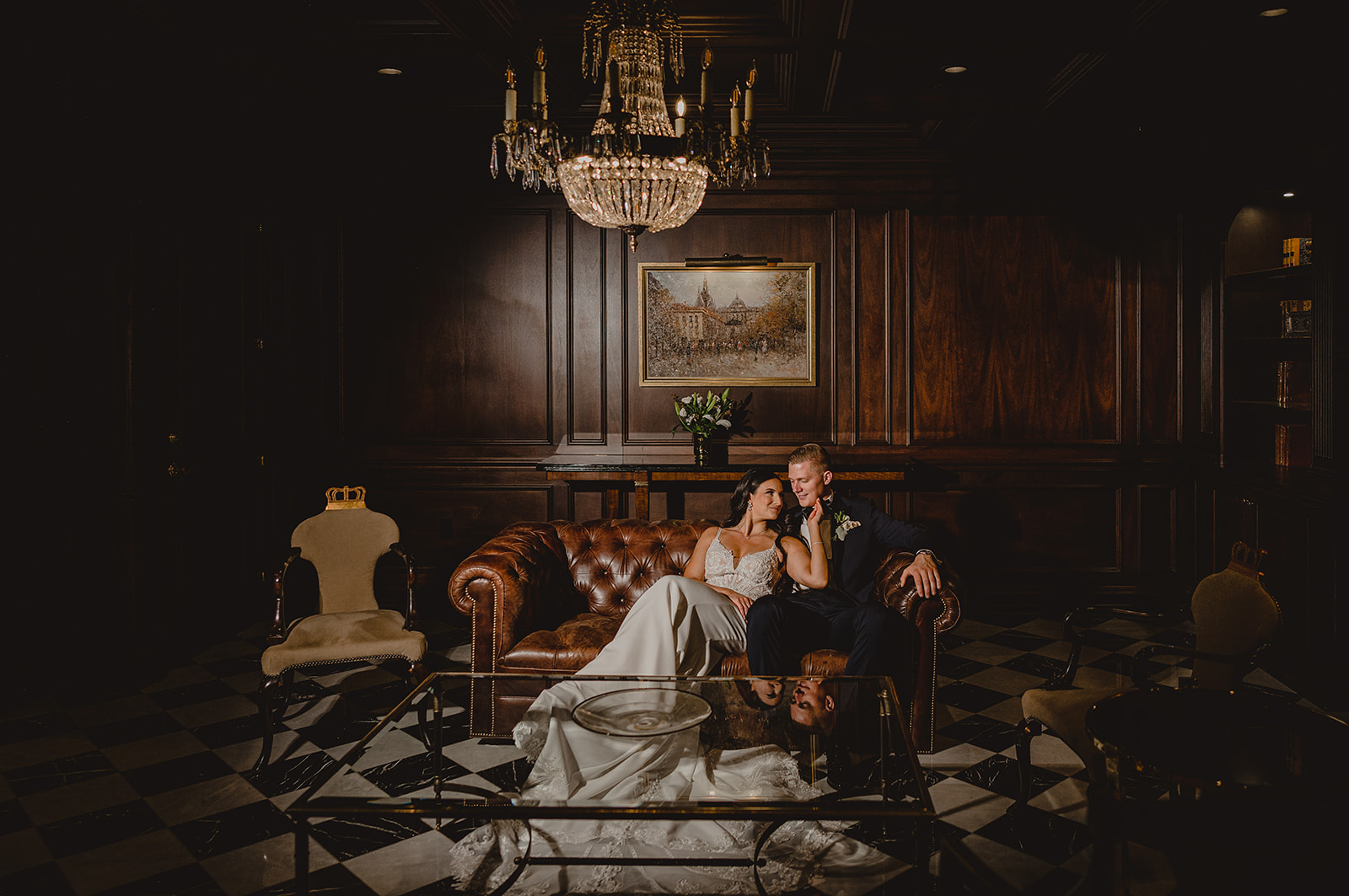 bride and groom lay on leather couch inside Park Chateau Estate