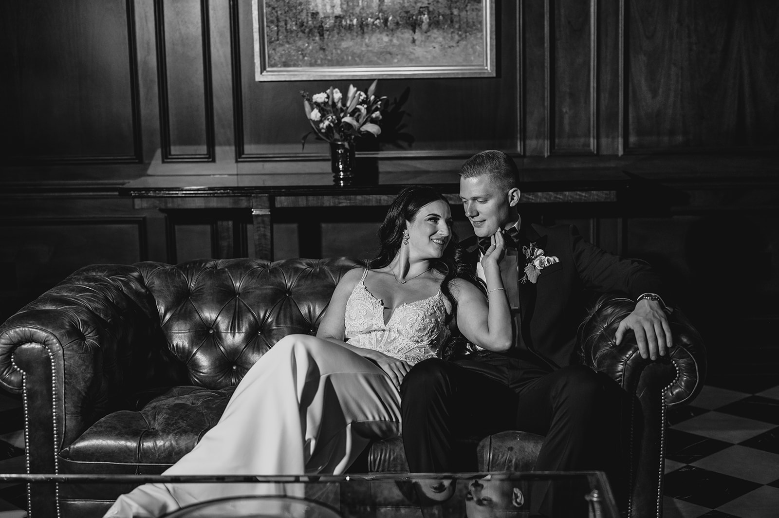 bride and groom sit on leather couch inside Park Chateau Estate