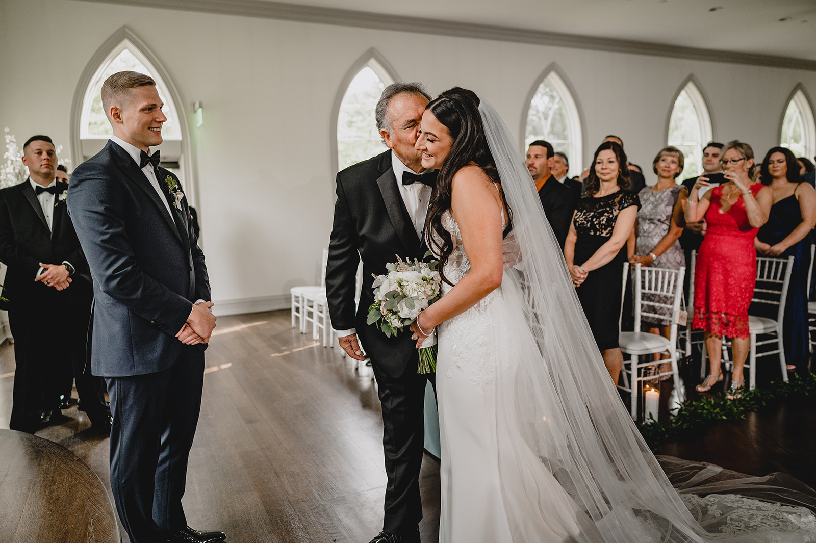 father kisses bride's cheek during ceremony inside the chapel at Park Chateau Estate