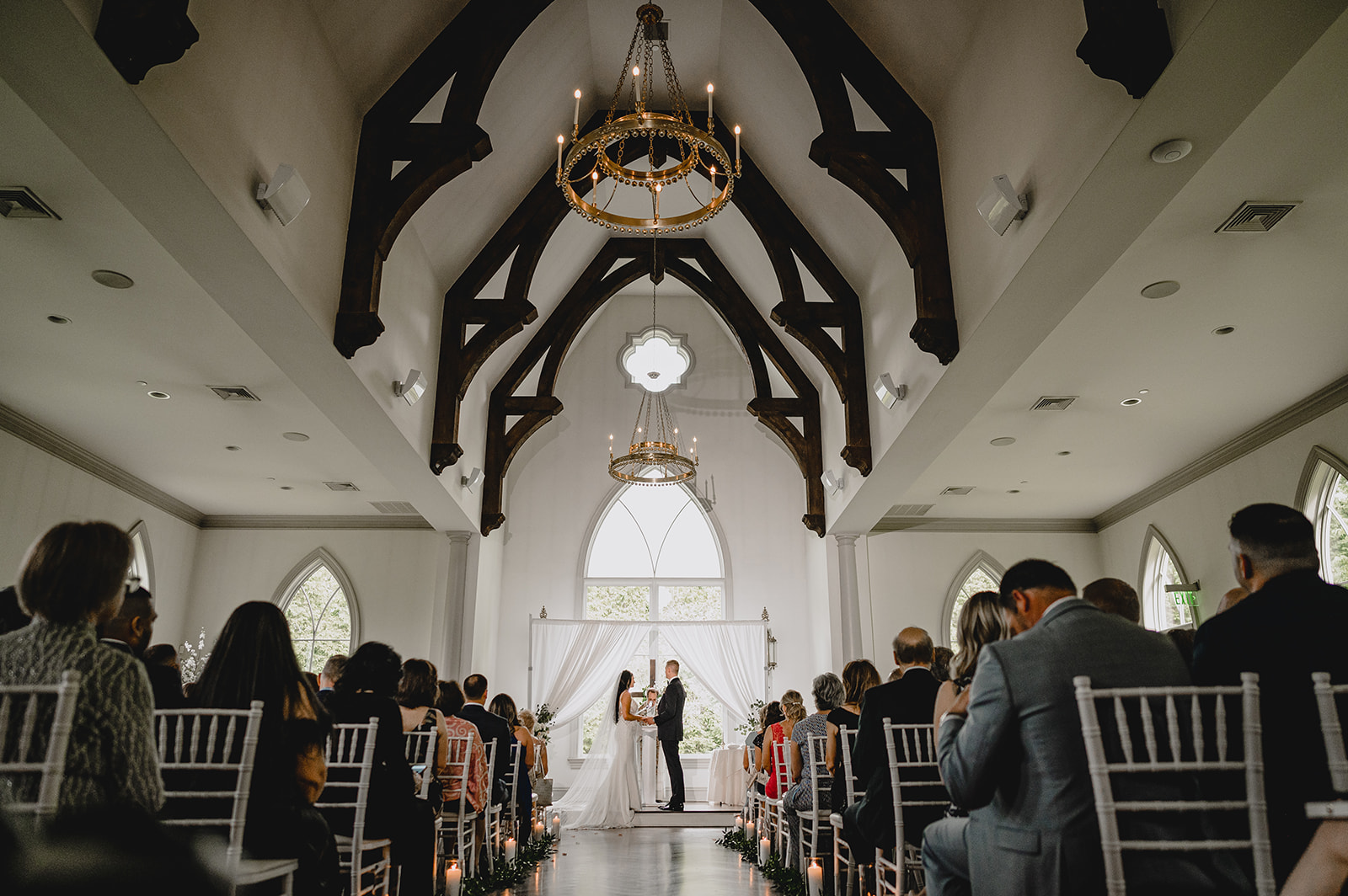 newlyweds hold hands inside ceremony inside the chapel at Park Chateau Estate