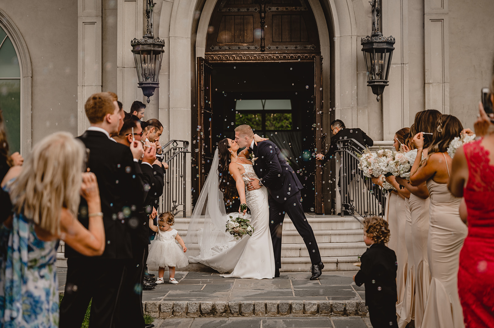 bride and groom kiss on streps of leaving the Park Chateau Estate chapel