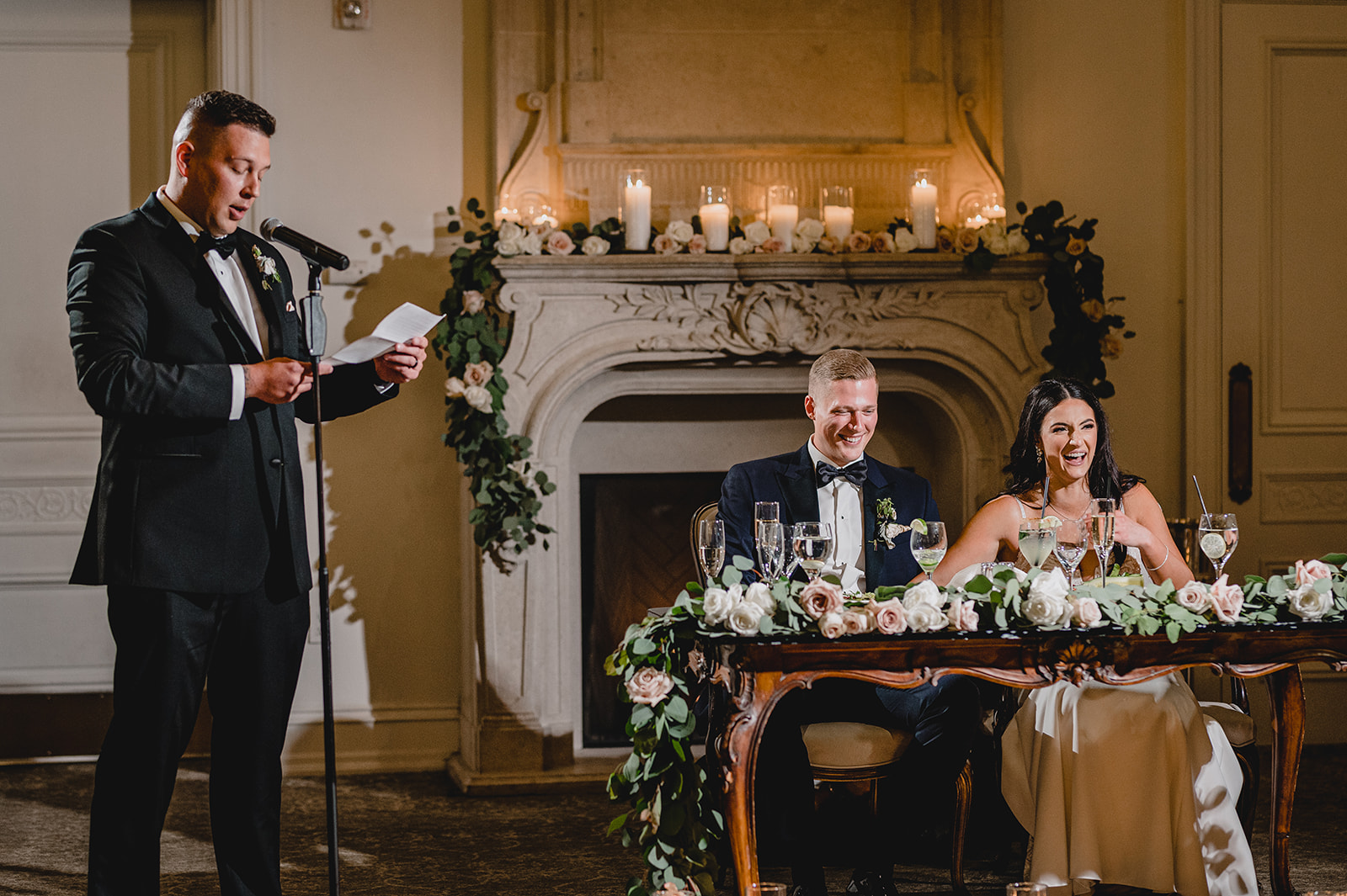 groomsman reads speech for bride and groom at sweetheart table
