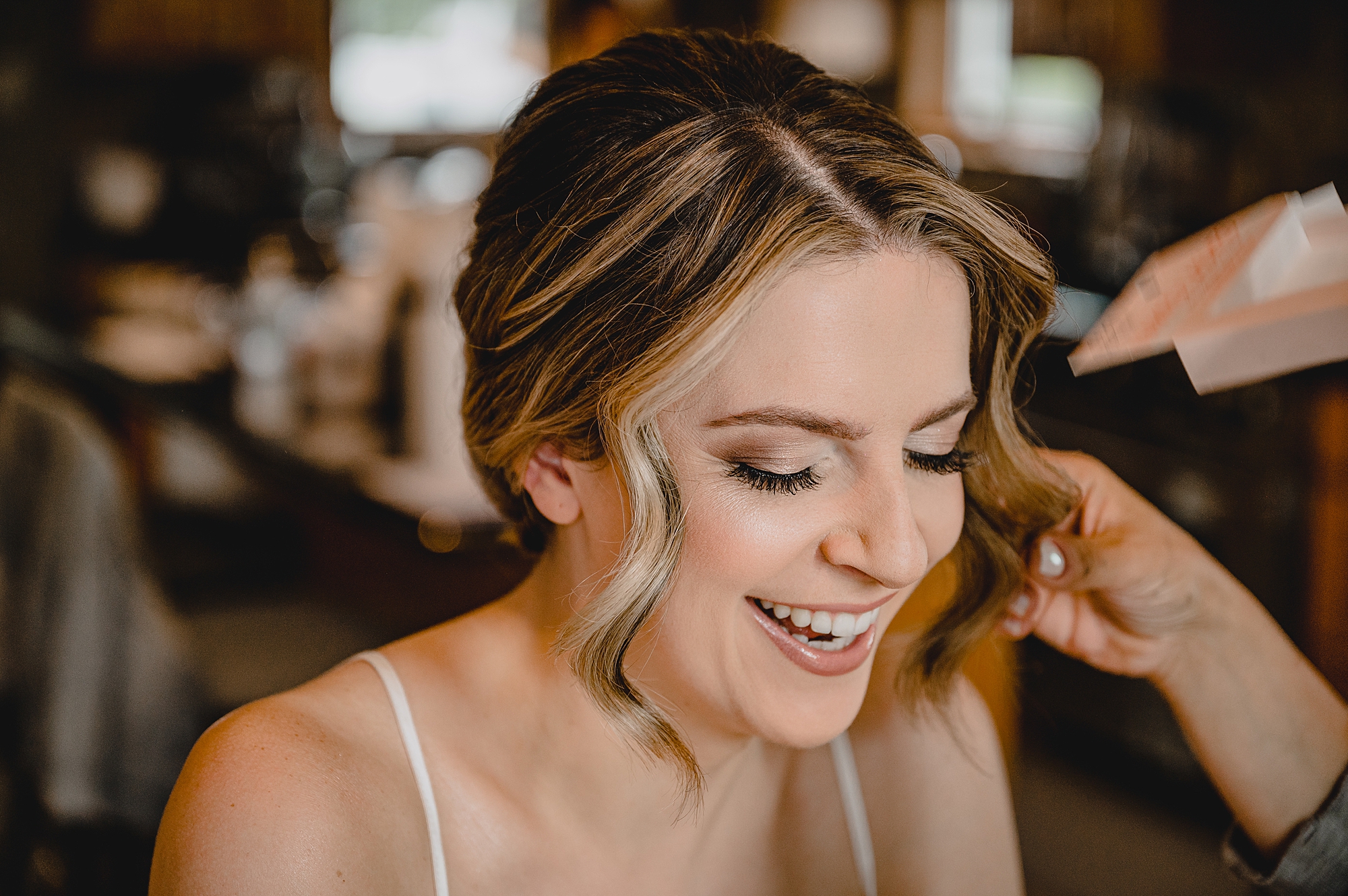 bride laughs while getting hair and makeup done