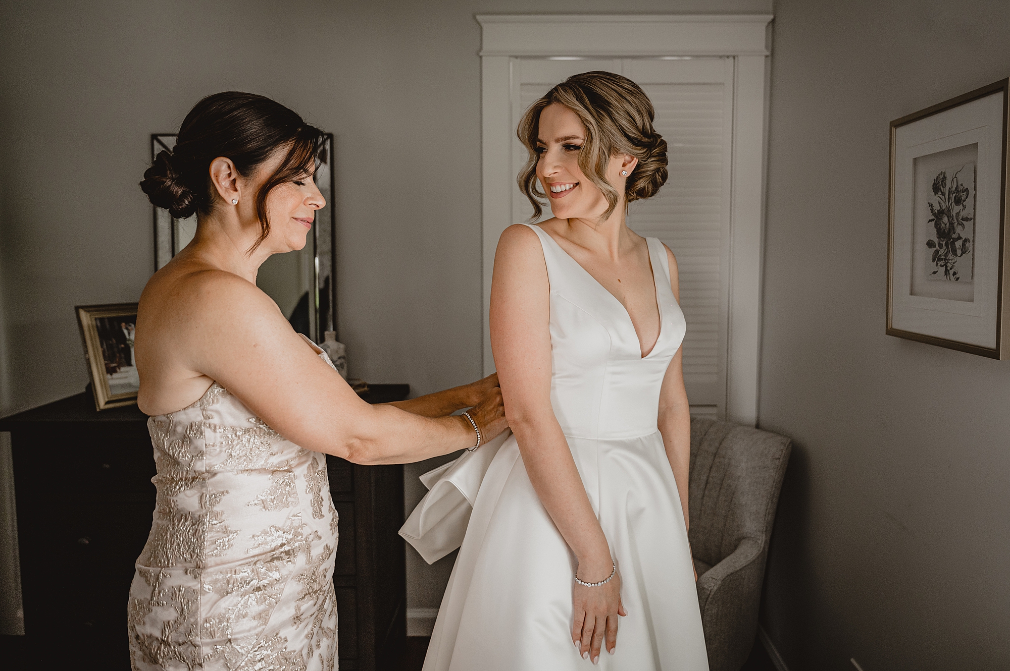bridesmaid buttons up bride into wedding dress