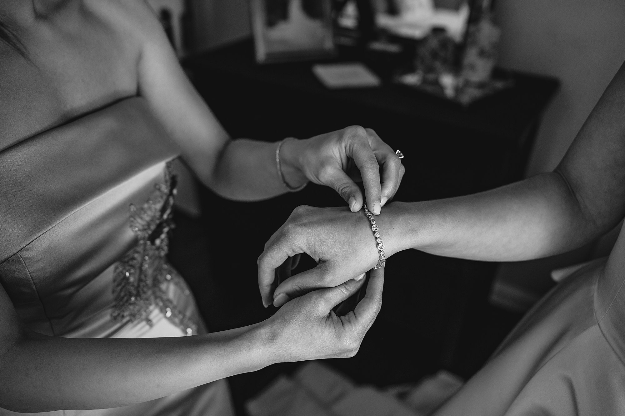 bridesmaid puts bracelet on bride's arm 