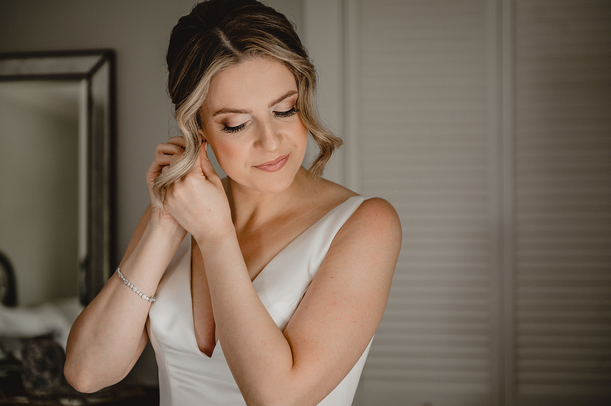 bride adjusts earring during prep for wedding day