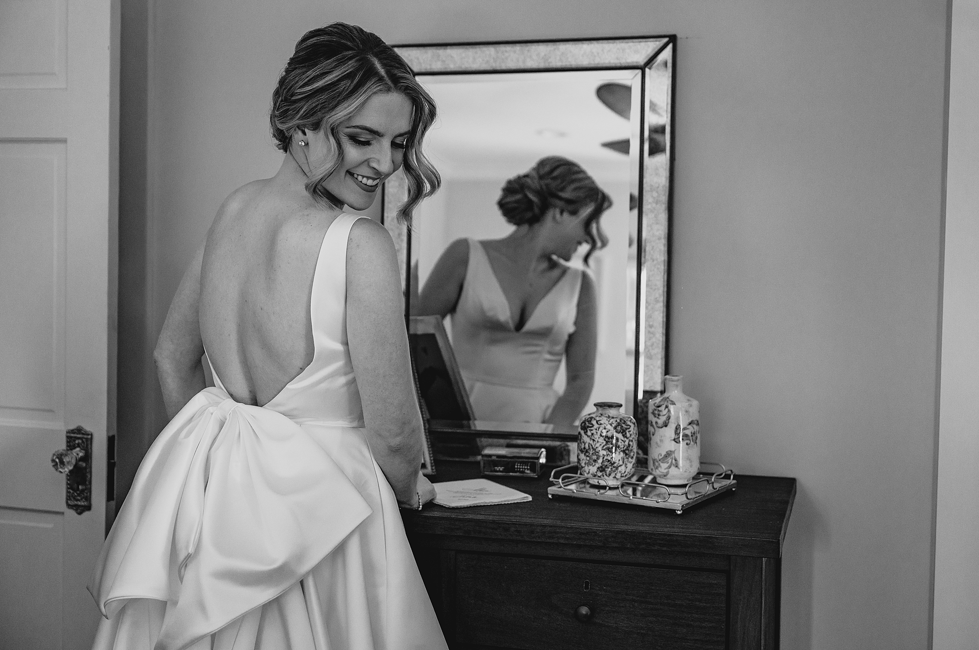 bride looks over shoulder in wedding dress with bow on back of wedding dress