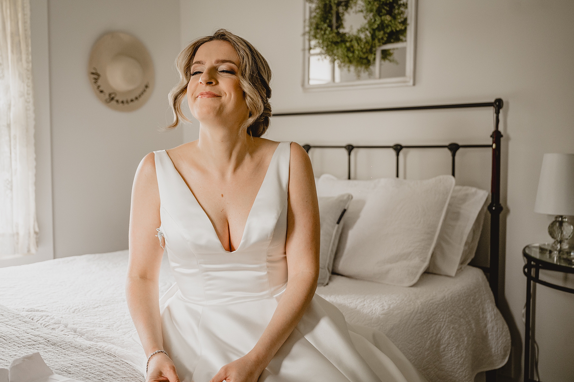 bride smiles sitting on bed before wedding day