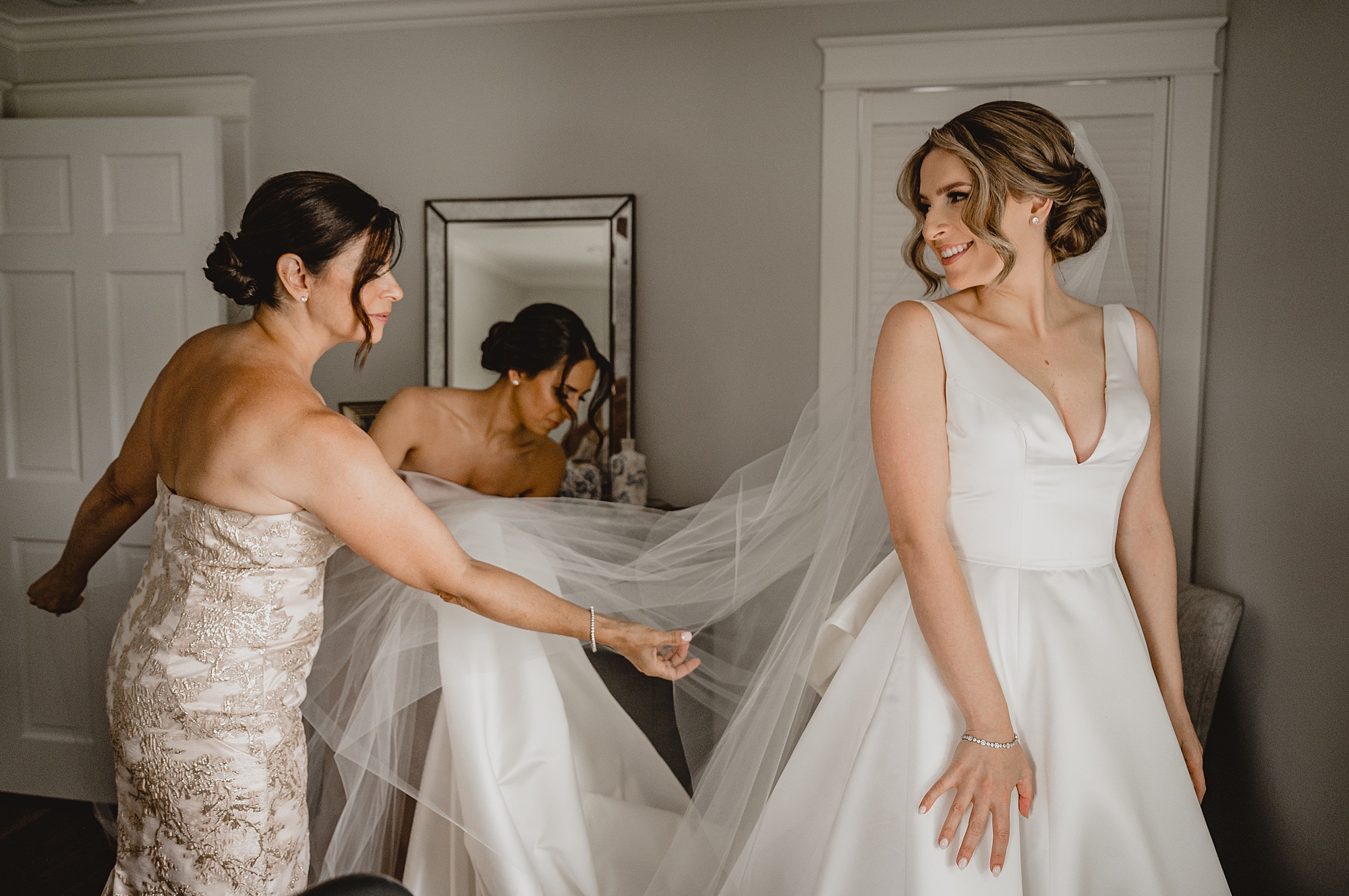 bridesmaids adjust veil behind bride