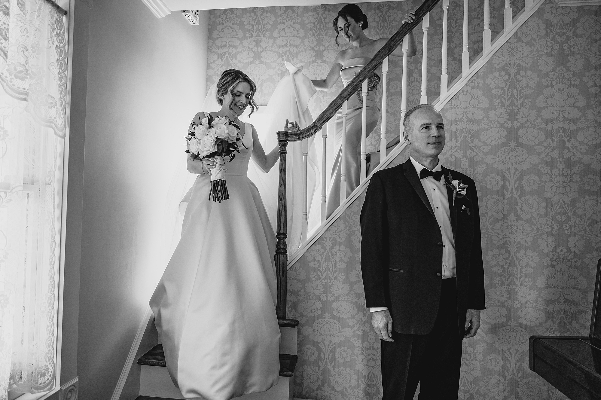 mother and bride walk down steps towards dad for first look