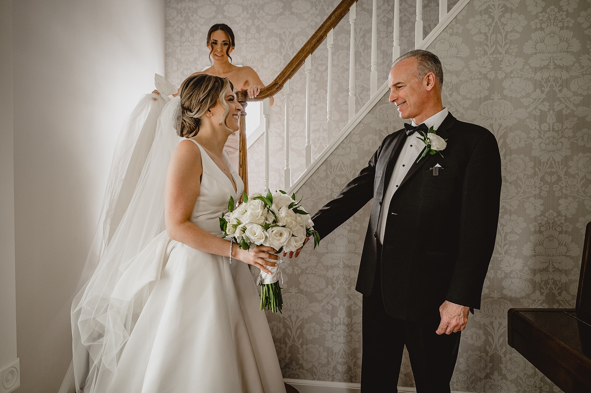 bride approaches dad during first look at bottom of staircase 