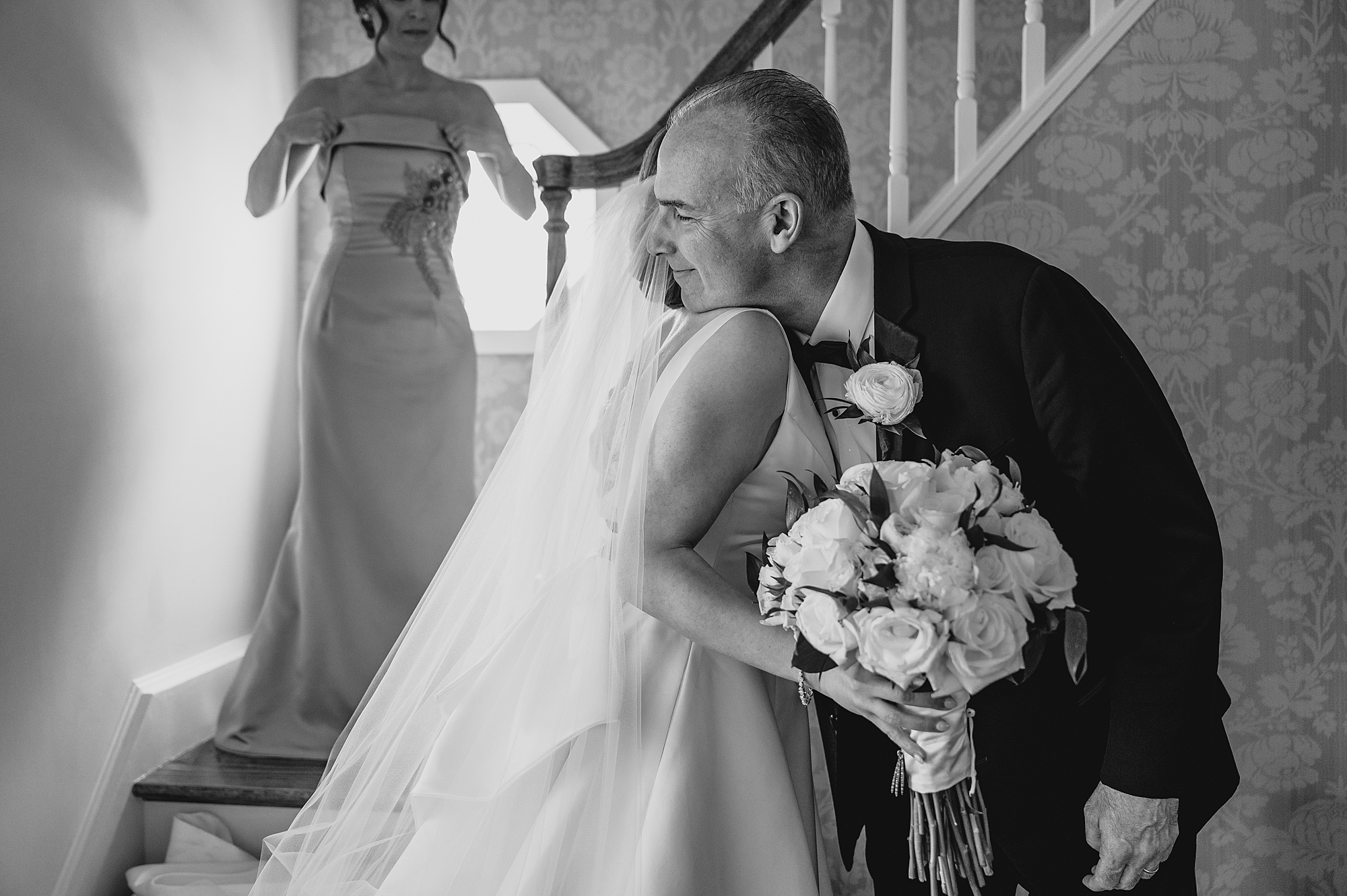 bride hugs dad during first look by staircase 