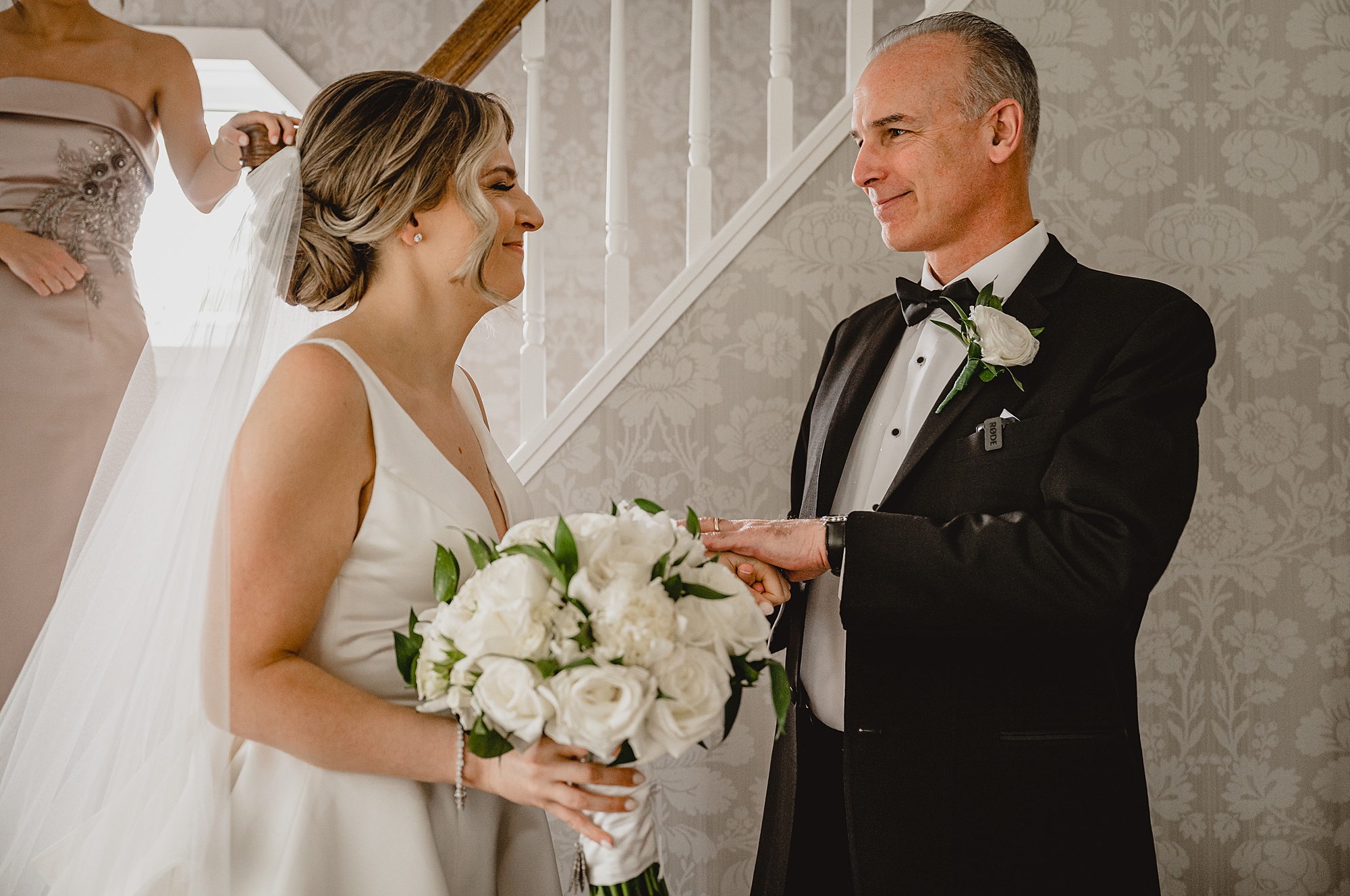 bride and dad smile during first look inside home 